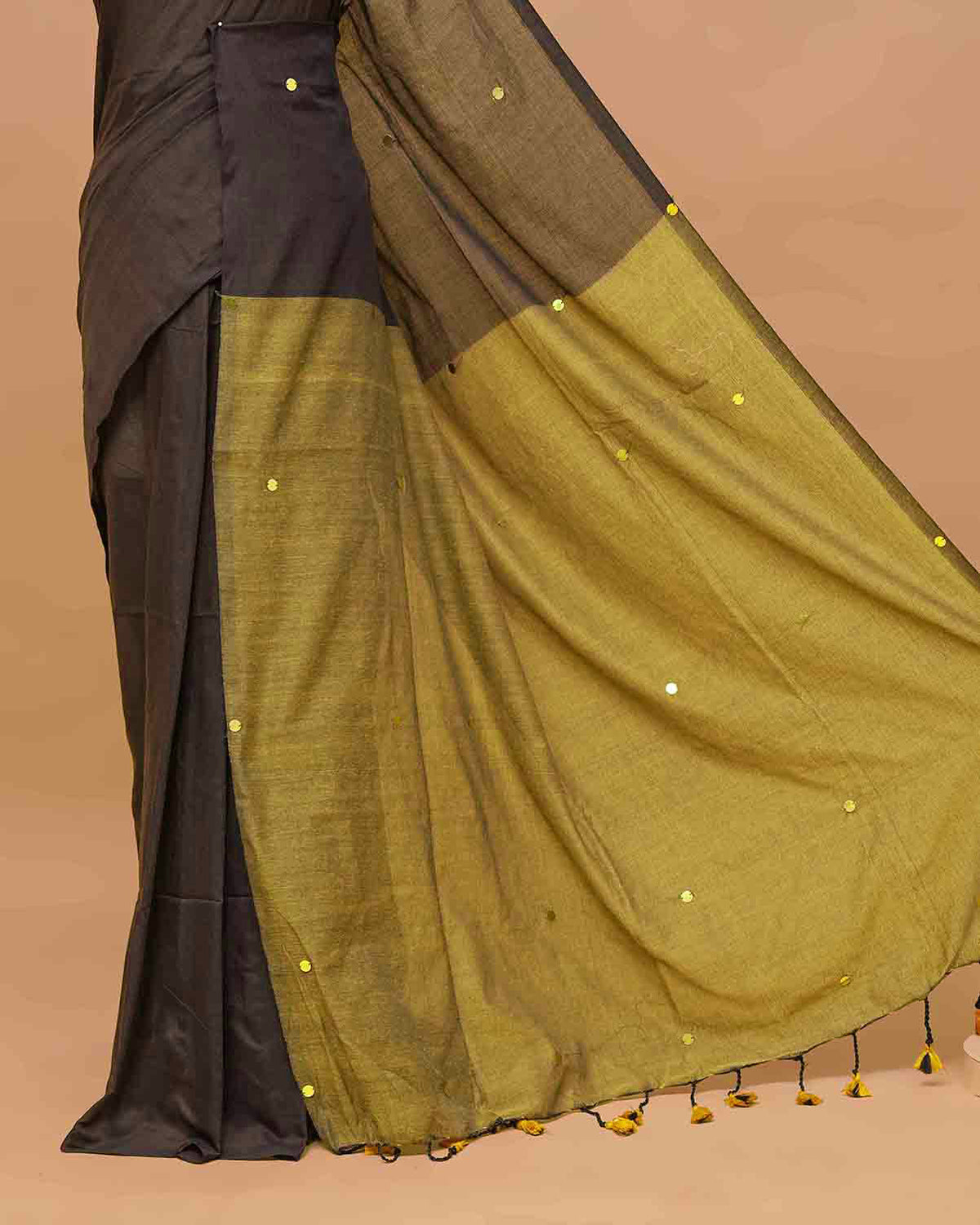 Black and Olive coloured half and half mul cotton saree featuring elegant sequin detailing on the body, finished with a beautiful pallu adorned with tassels.