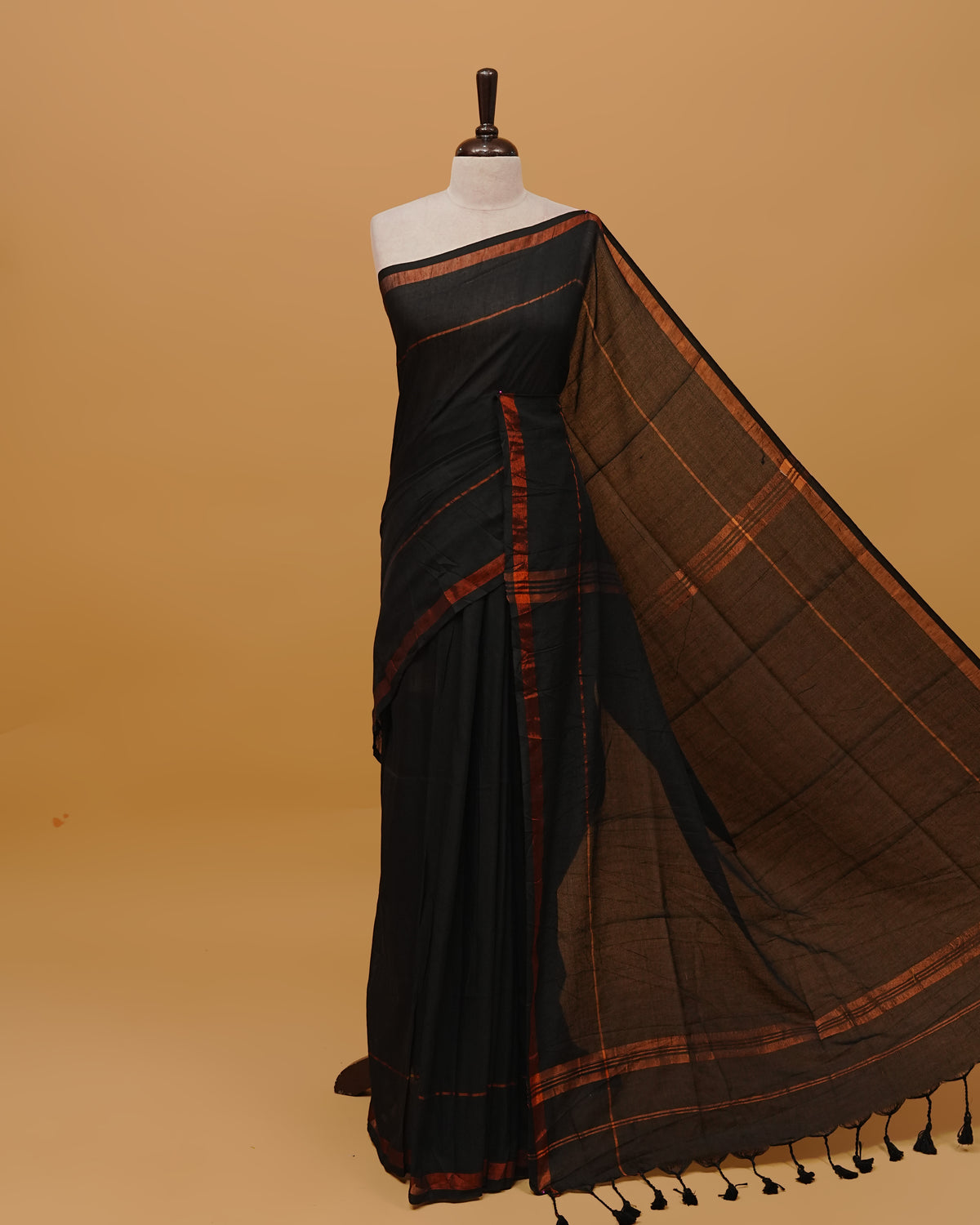 Black Colour Mul Cotton Saree Featuring Plain body. Copper zari Border & Copper zari Strips on pallu comes With Tassels