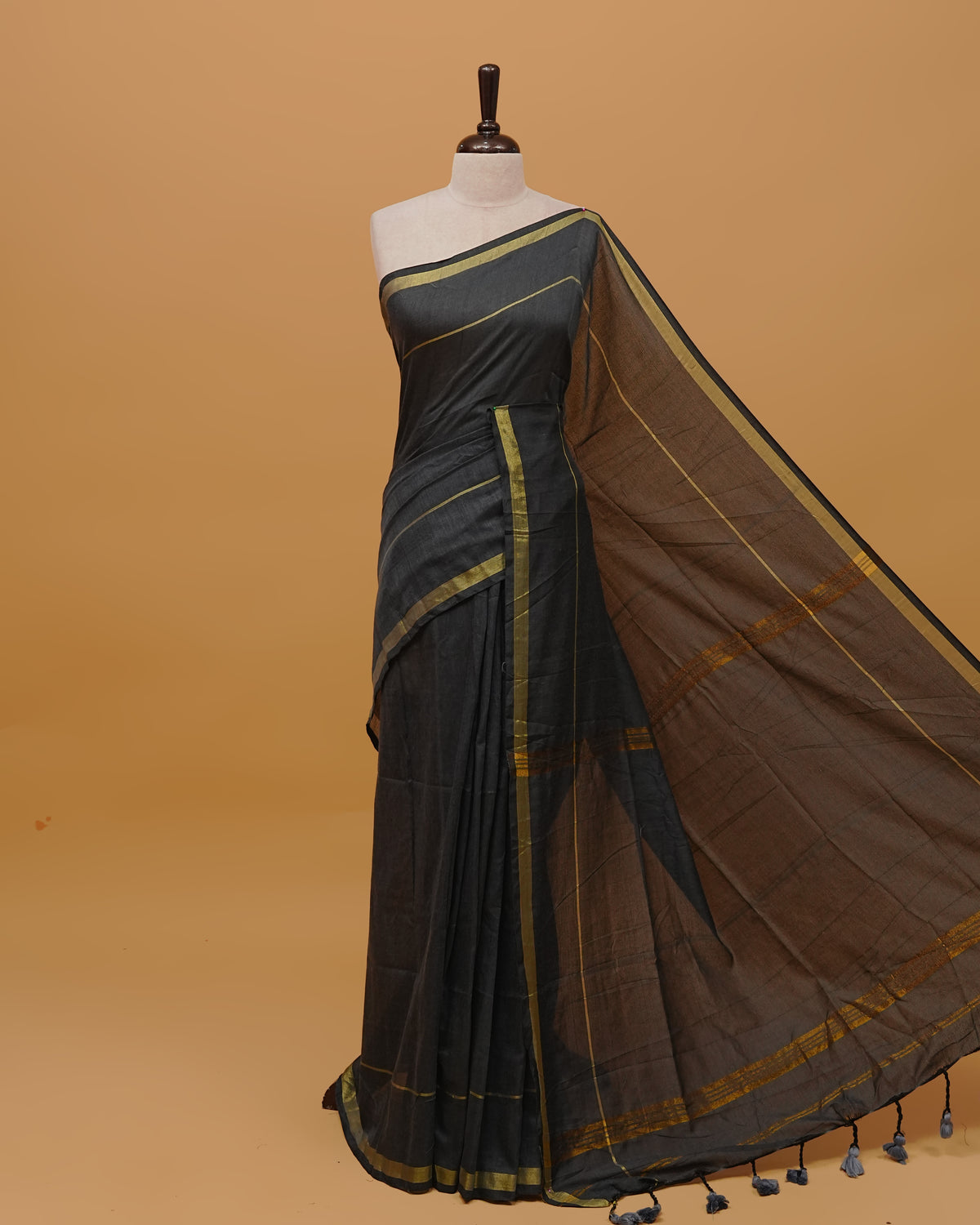 Greyish Black Colour Mul Cotton Saree Featuring Plain body. Gold zari Border & Golden Strips on pallu comes With Tassels