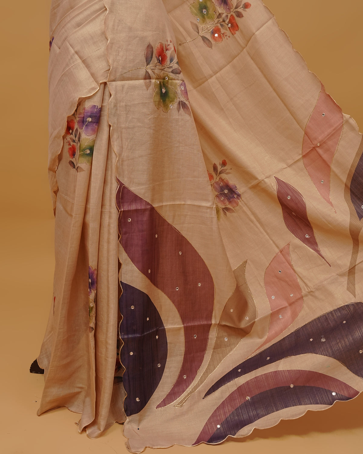 Cream colour Semi Tissue saree featuring Floral Motifs Design and Mirror Work on the body, a Scallop border, and a pallu finished with tassels, paired with a matching blouse piece.