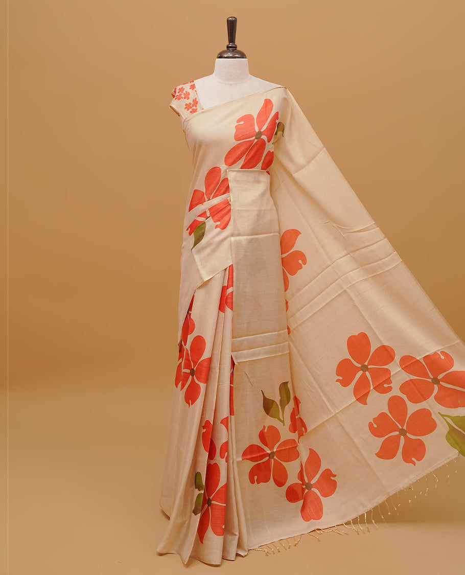 Cream colour semi tissue saree featuring floral prints on the body, without border & pallu finished with tassels. Paired with a matching blouse piece.