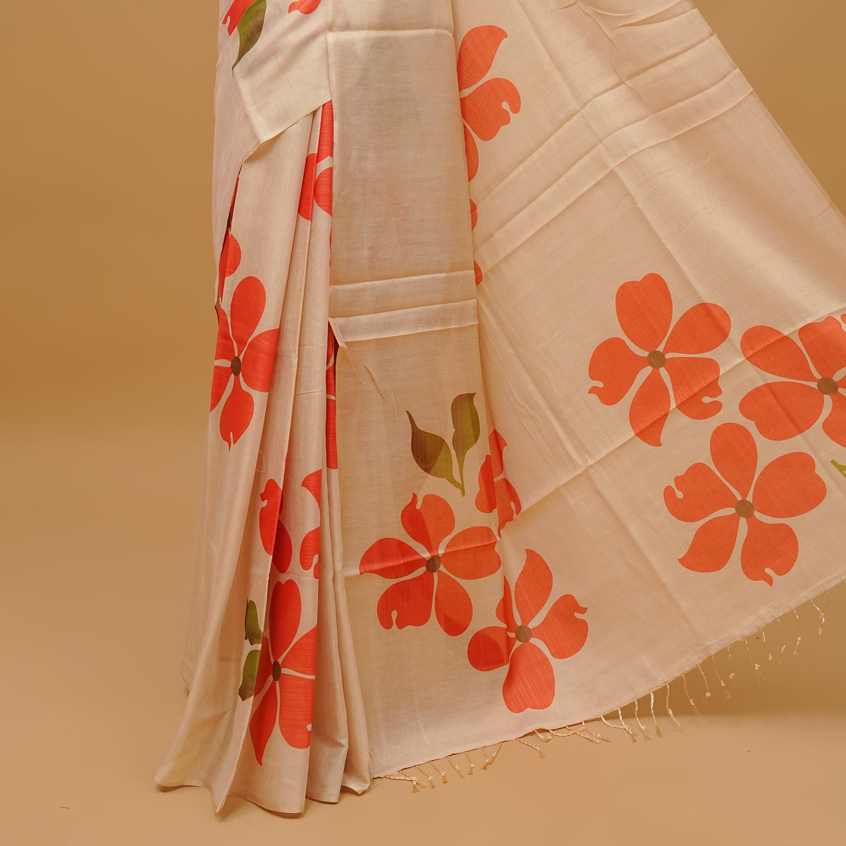 Cream colour semi tissue saree featuring floral prints on the body, without border & pallu finished with tassels. Paired with a matching blouse piece.