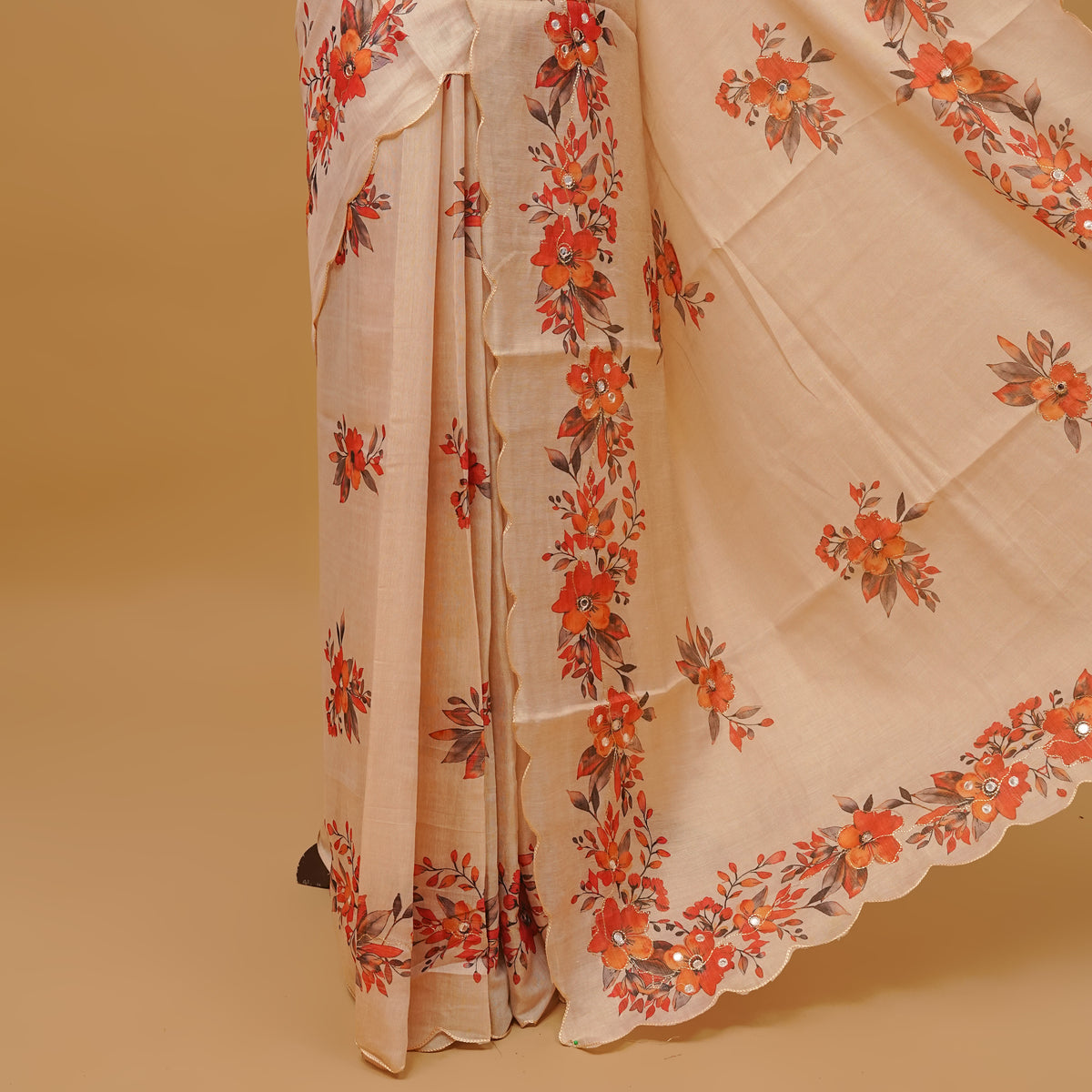Cream colour semi tissue saree featuring floral prints with Mirror Work on body, with scallop border & pallu finished with tassels. Paired with a matching blouse piece.