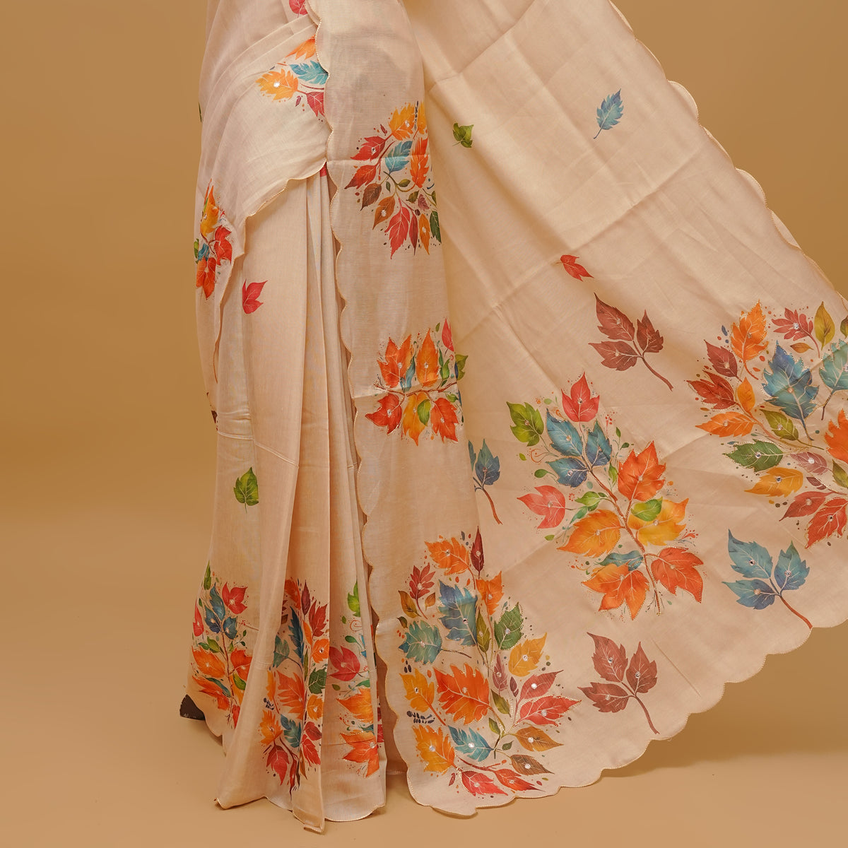 Cream colour semi tissue saree featuring Flowers prints and Mirror Work on the body, with scallop border & pallu finished with tassels. Paired with a matching blouse piece.