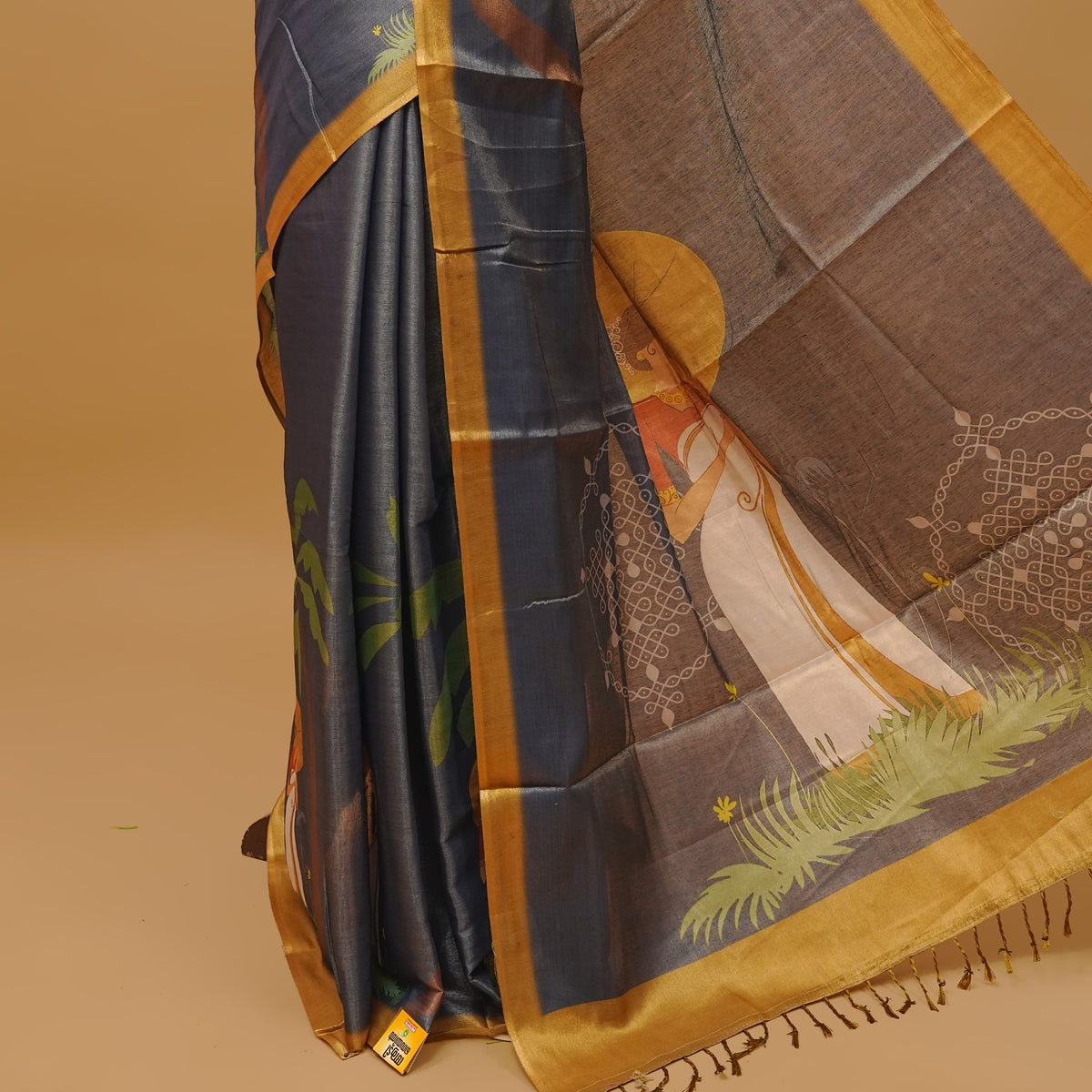 Grayish blue colour semi tissue saree featuring a Lady prints on the body, with gold colour border & pallu finished with tassels. Paired with a matching blouse piece.