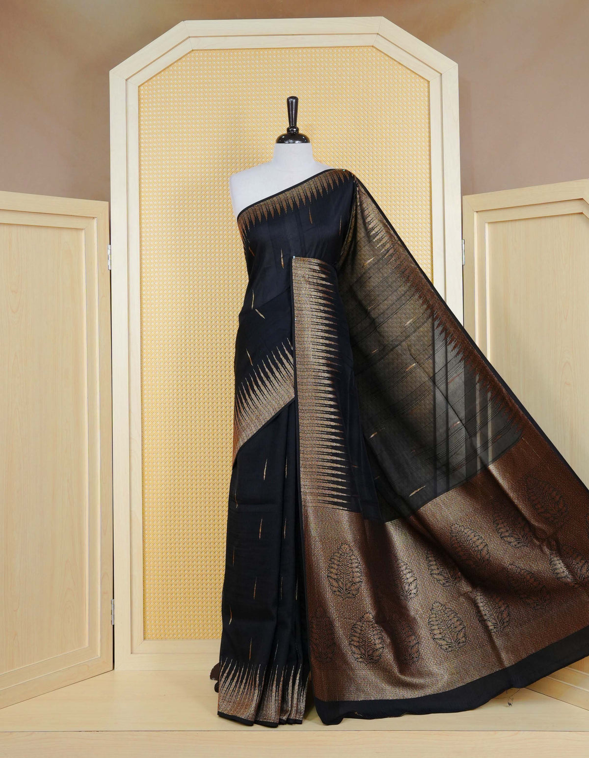 Black colour semi banaras tussar georgette saree featuring gold zari pattern on body, finished with gold zari temple border and paired with matching blouse piece.