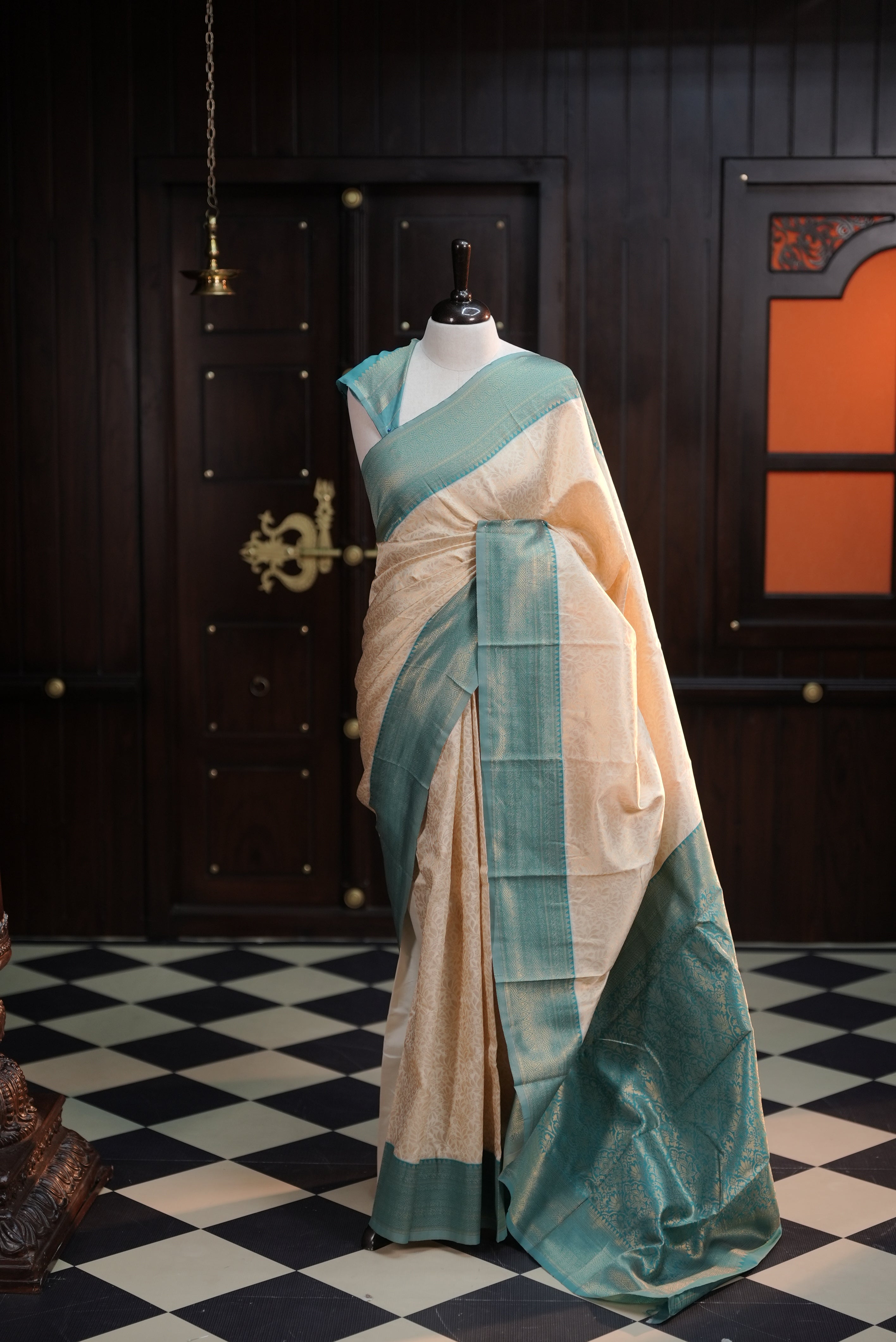 Cream colour semi tissue saree highlighting golden thread worked body, contrast teal green colour border, pallu and comes with matching blouse piece.
