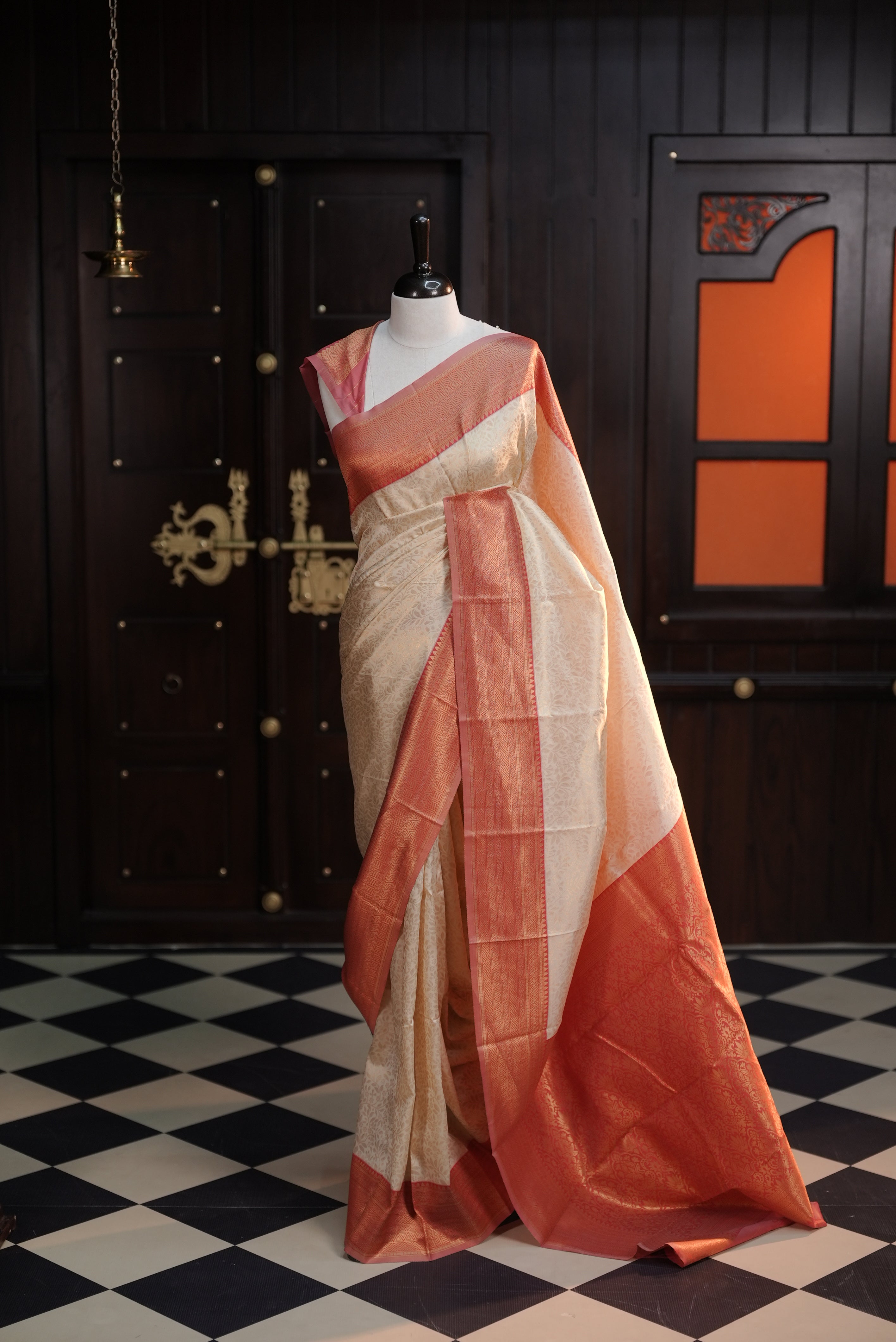 Cream colour semi tissue saree highlighting golden thread worked body, contrast red colour border, pallu and comes with matching blouse piece.