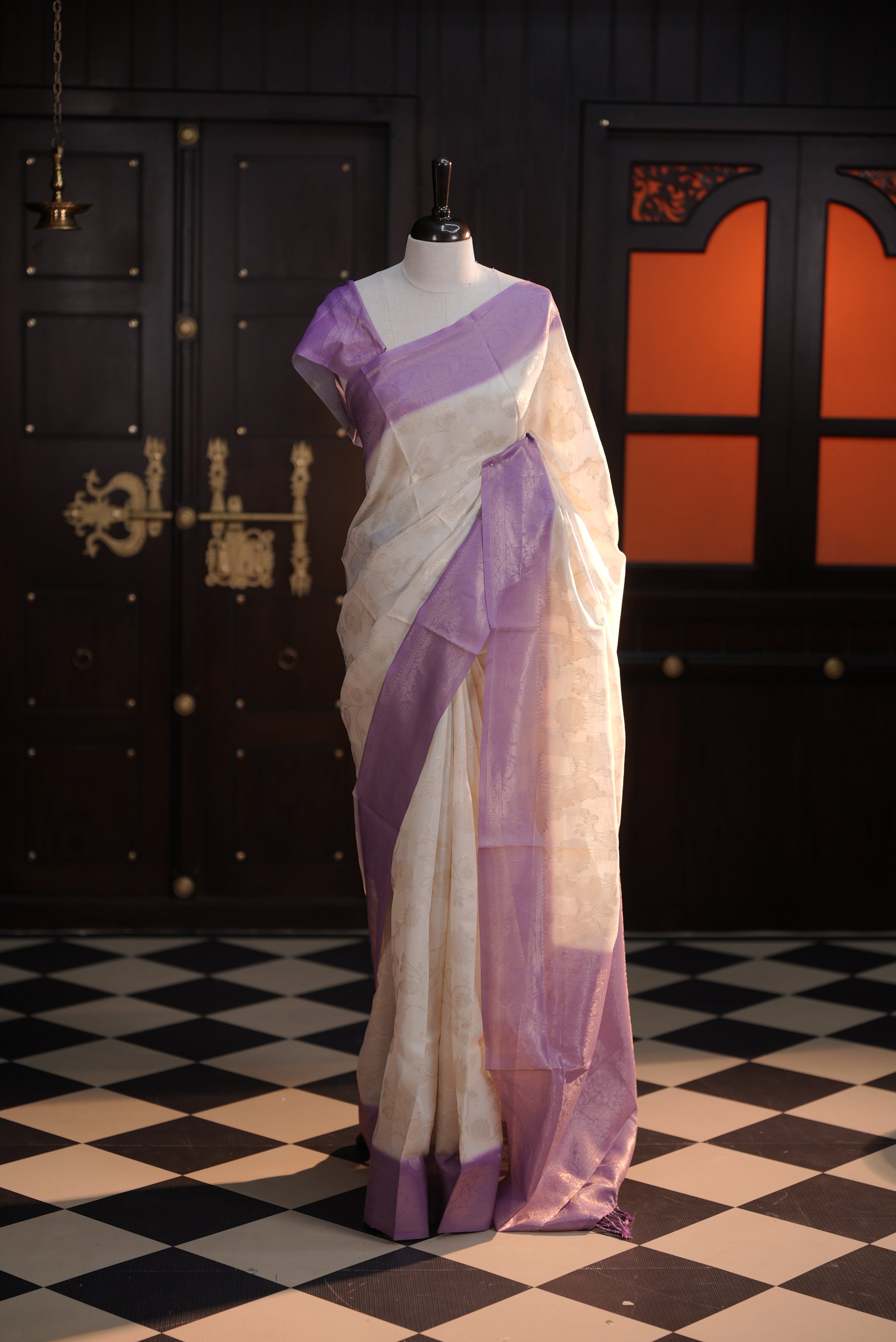 Cream colour Litchi silk saree highlighting antique floral thread pattern on body, contrast Lavender colour border, pallu and comes with matching blouse piece.