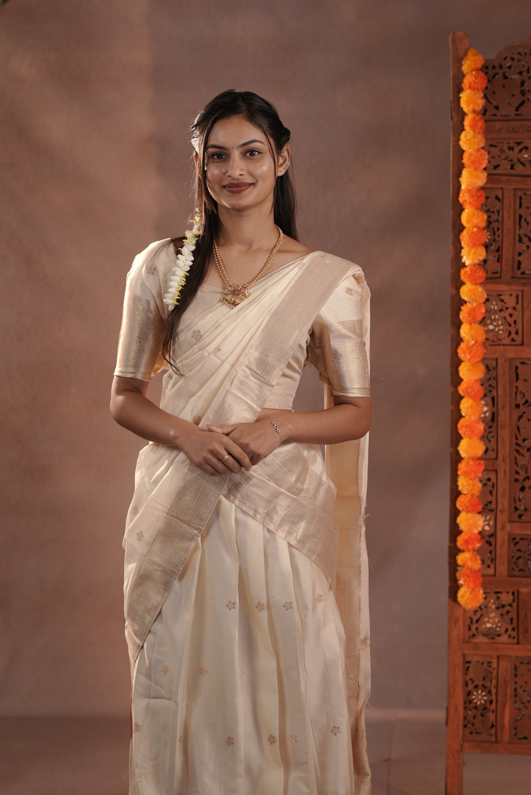 Off white colour Semi Stitched Tissue Banaras Dhavani Set Featuring Skirt with Gold zari buttas & Traditional border, paired with Cream Blouse material with gold zari buttas, finishing with same colour with gold zari buttas & scallop border Dupatta.