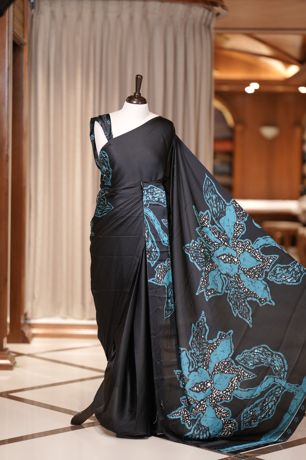 Black colour modal satin saree featuring soft satin touch fabric with bold Blue colour floral prints across the body and matching pallu & Comes with a coordinated floral printed blouse for a chic, graceful look