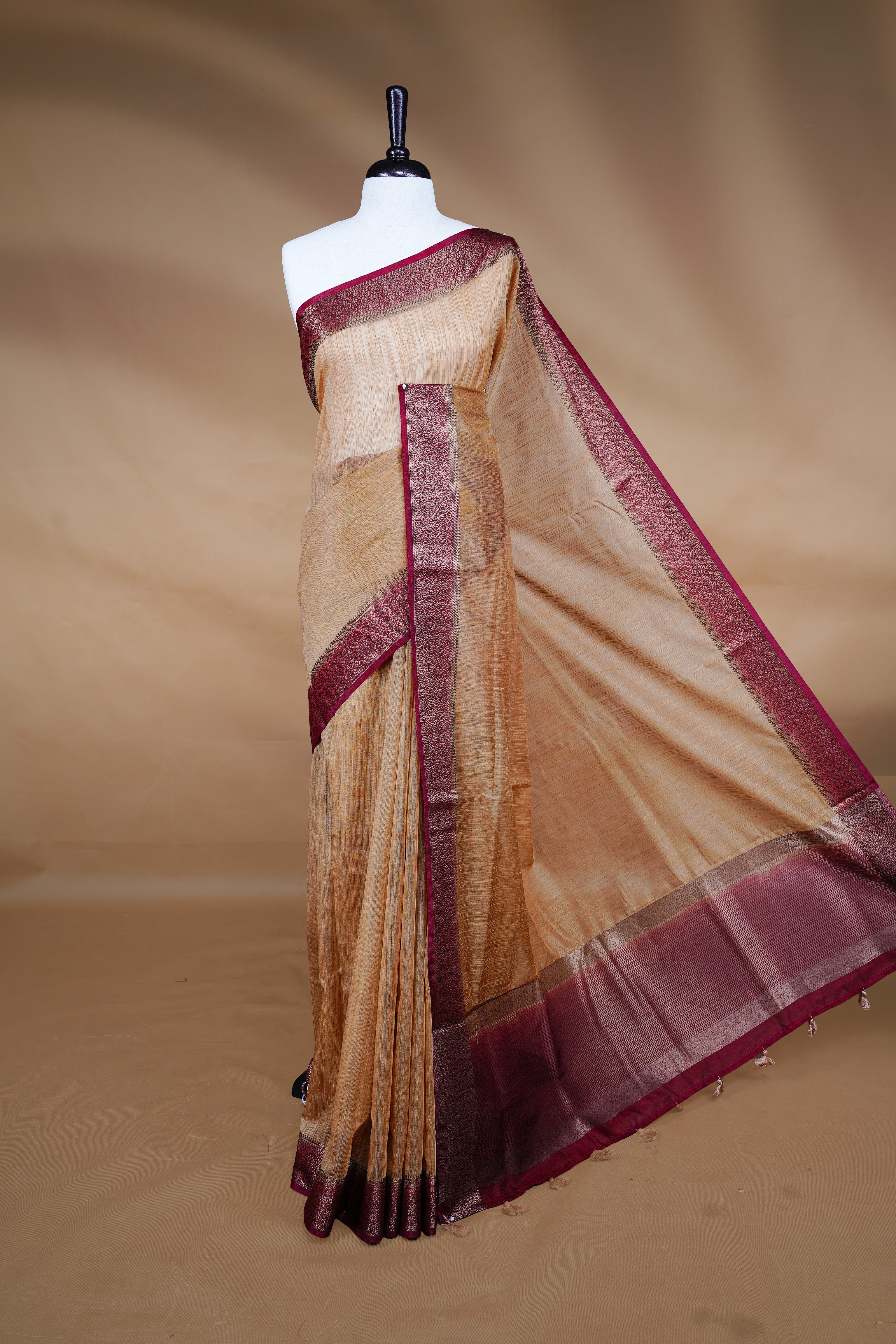 Beige colour Semi linen saree featuring Elegant plain body, complemented by contrast Maroon colour With Antique zari border, paired with matching blouse piece.