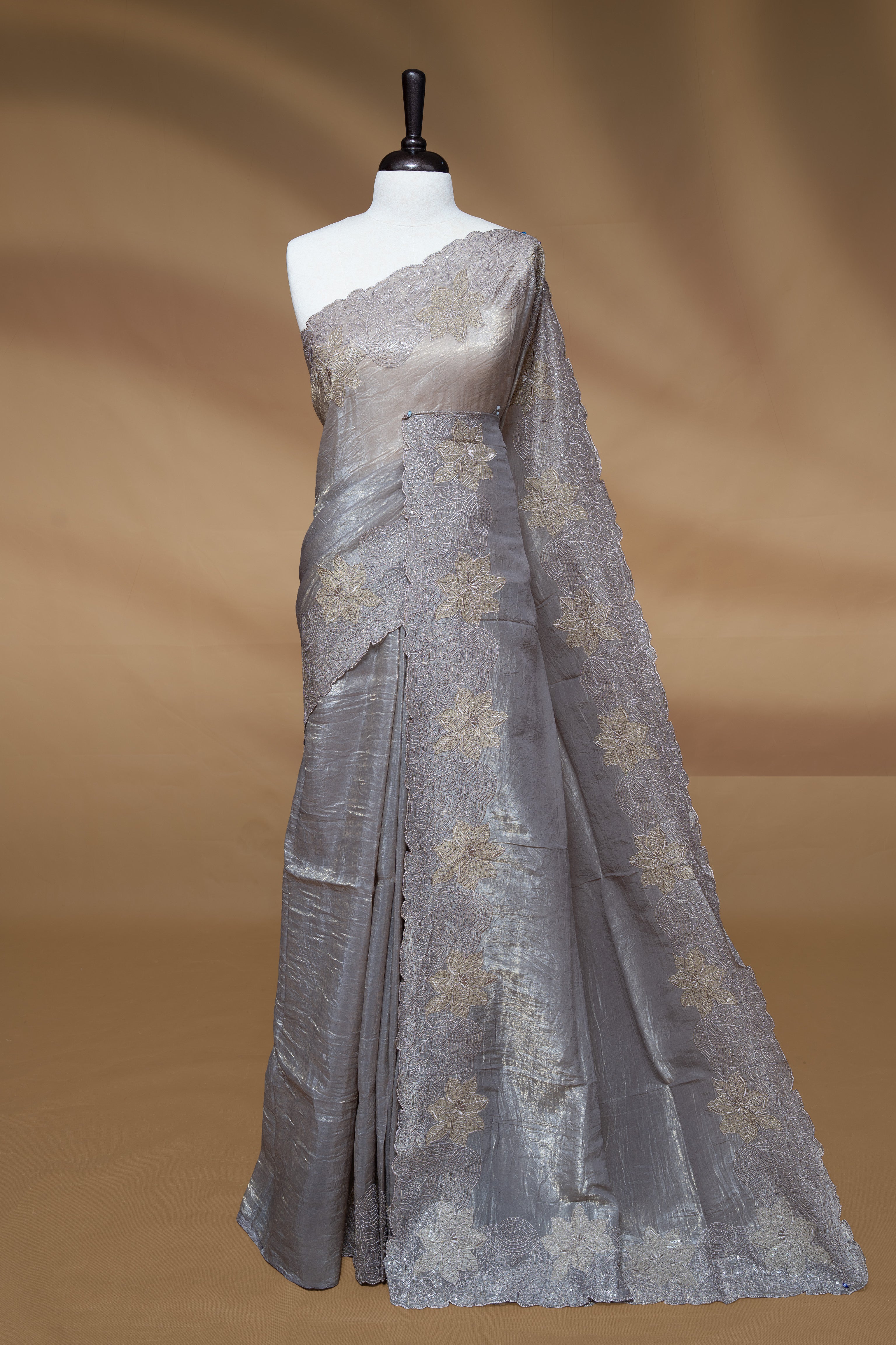 Grey colour Crush Organza Featuring Plain body, Enrich with Floral thread pattern with sequins & scalp border, paired with matching blouse piece.