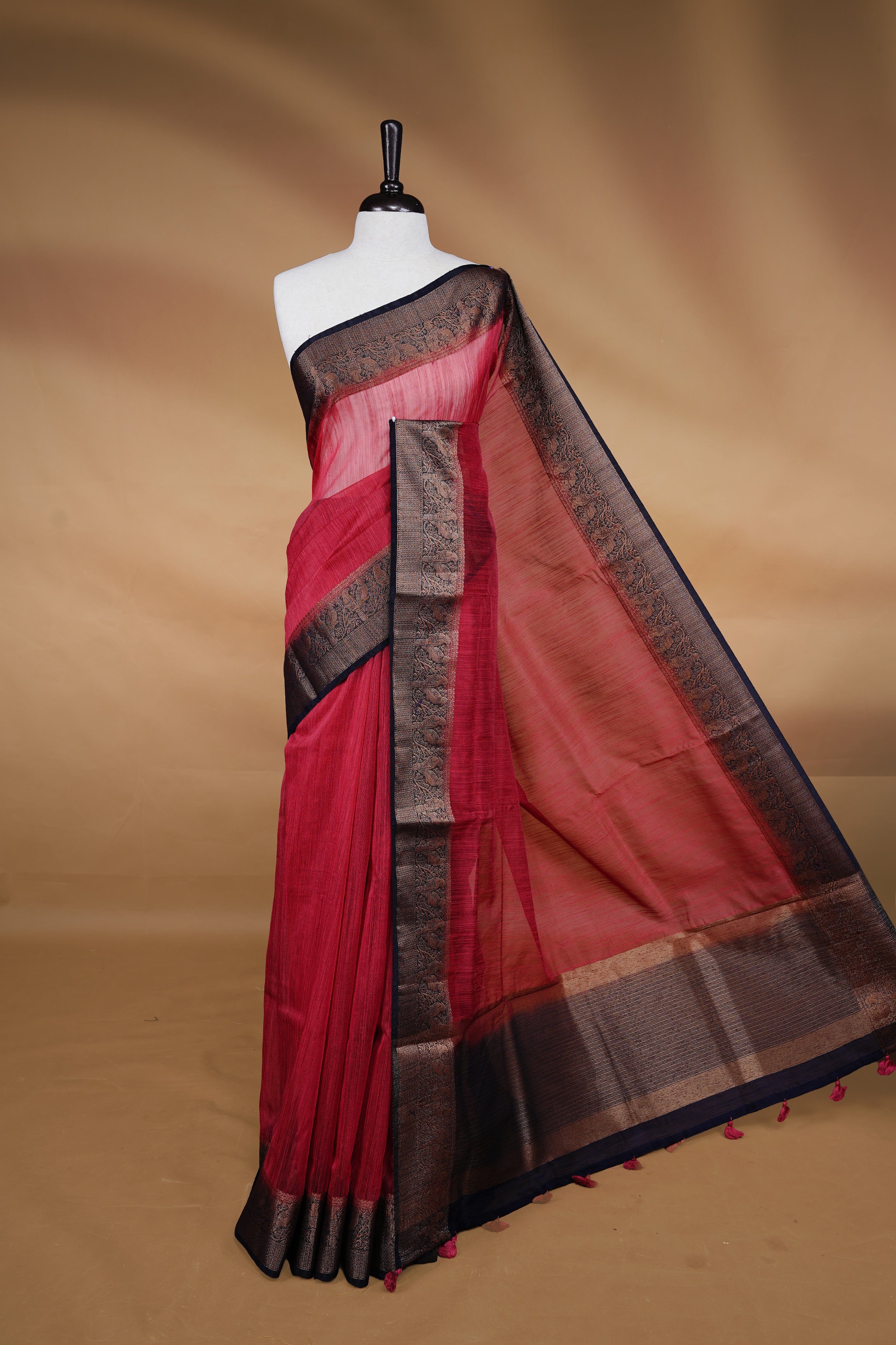 Saffron red colour Semi linen saree featuring Elegant plain body, complemented by contrast Navy Blue colour With Antique zari border, paired with matching blouse piece.