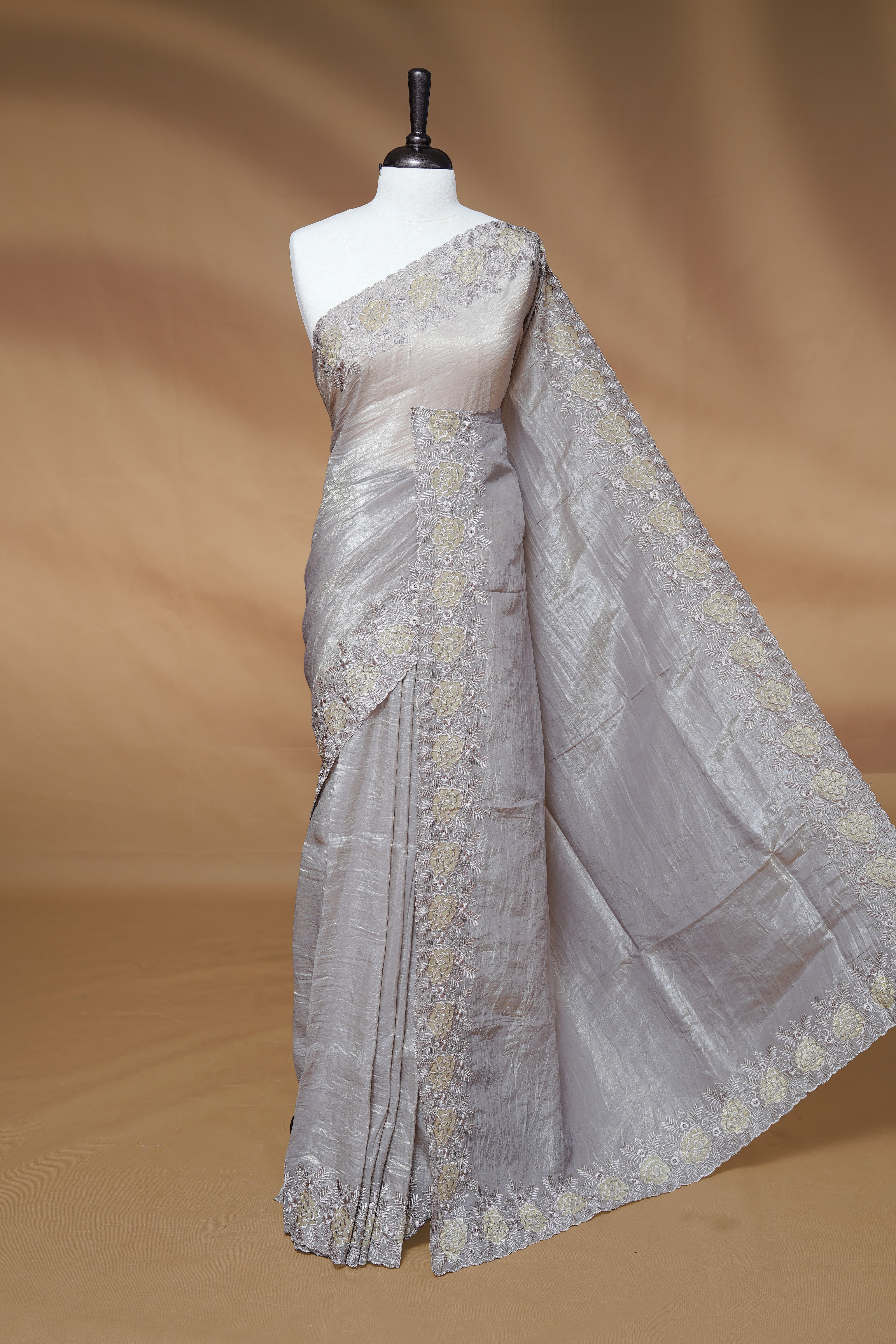 Grey colour Crush Organza Featuring Plain body, Enrich with Floral thread pattern & scalp border, paired with matching blouse piece.
