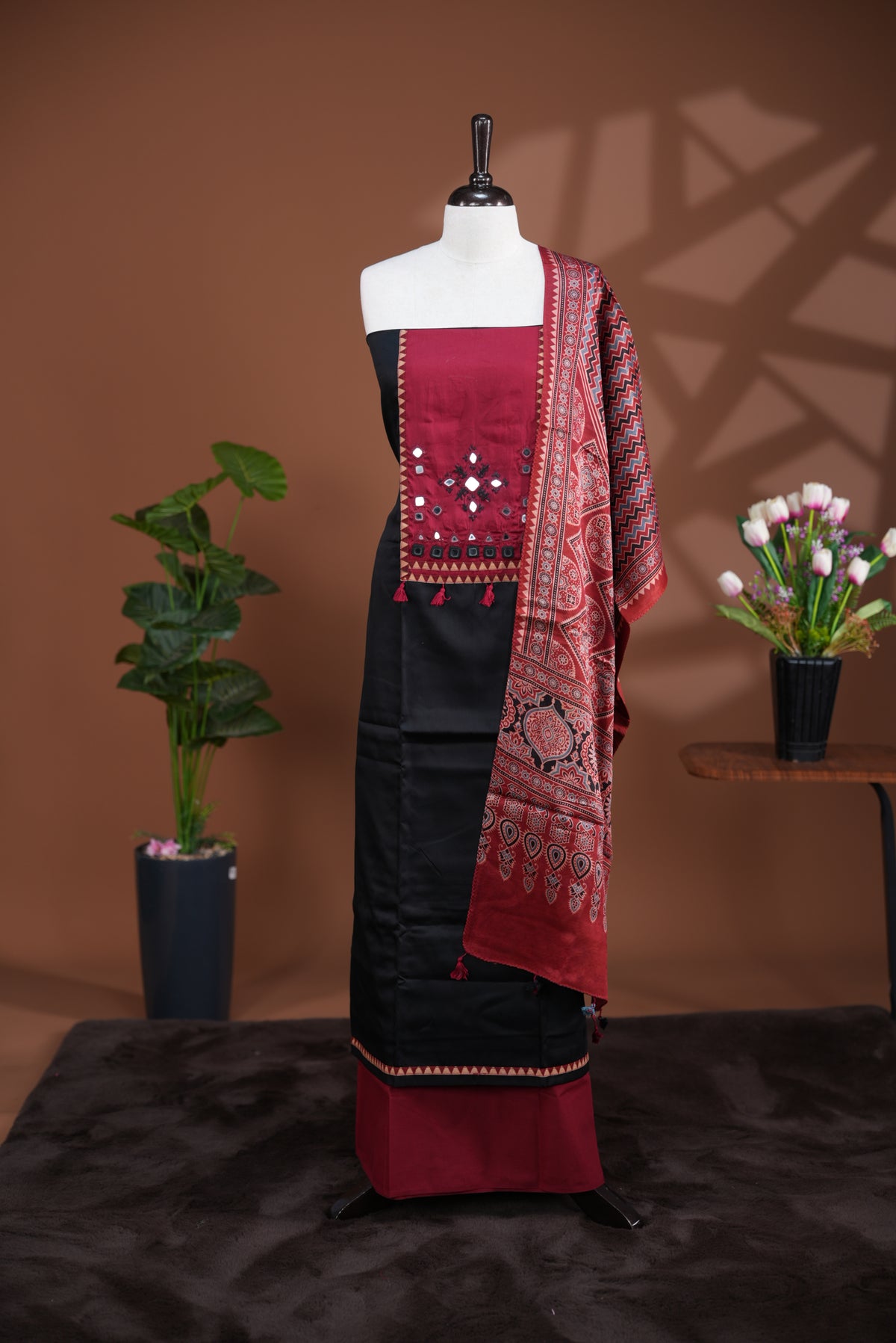 Black colour Jam Satin salwar material, Plain body with mirror & thread work on neck portion, matching bottom and Dupatta with ajrak print.