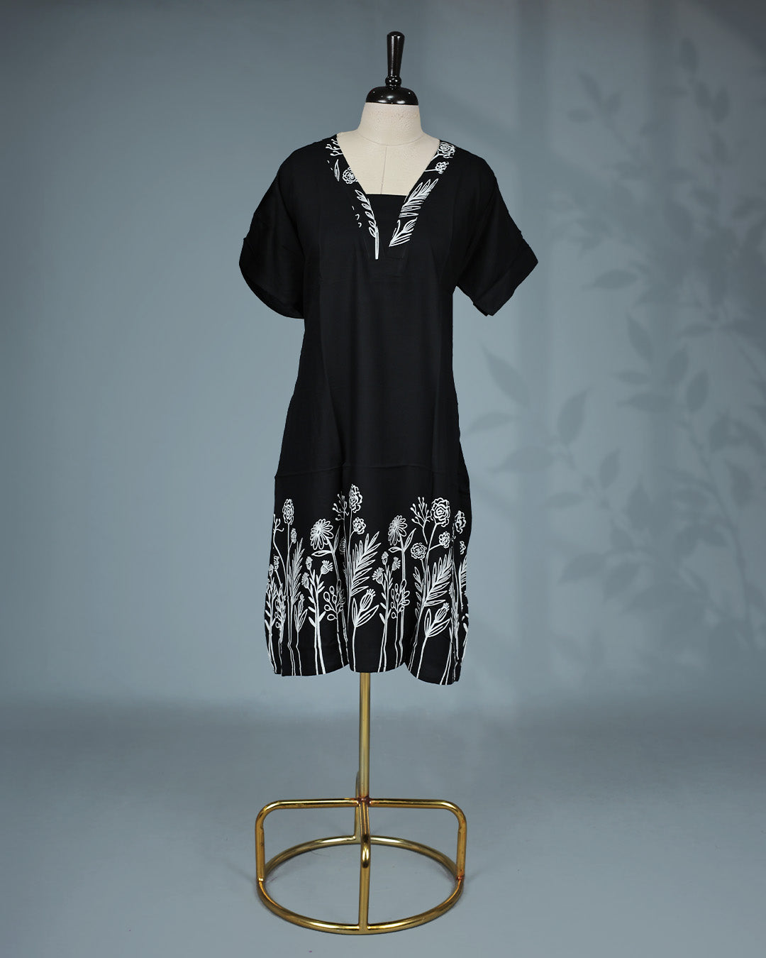 Black colour nighty featuring white floral prints on the V-neckline and hem, short sleeves and a mid-length fit.