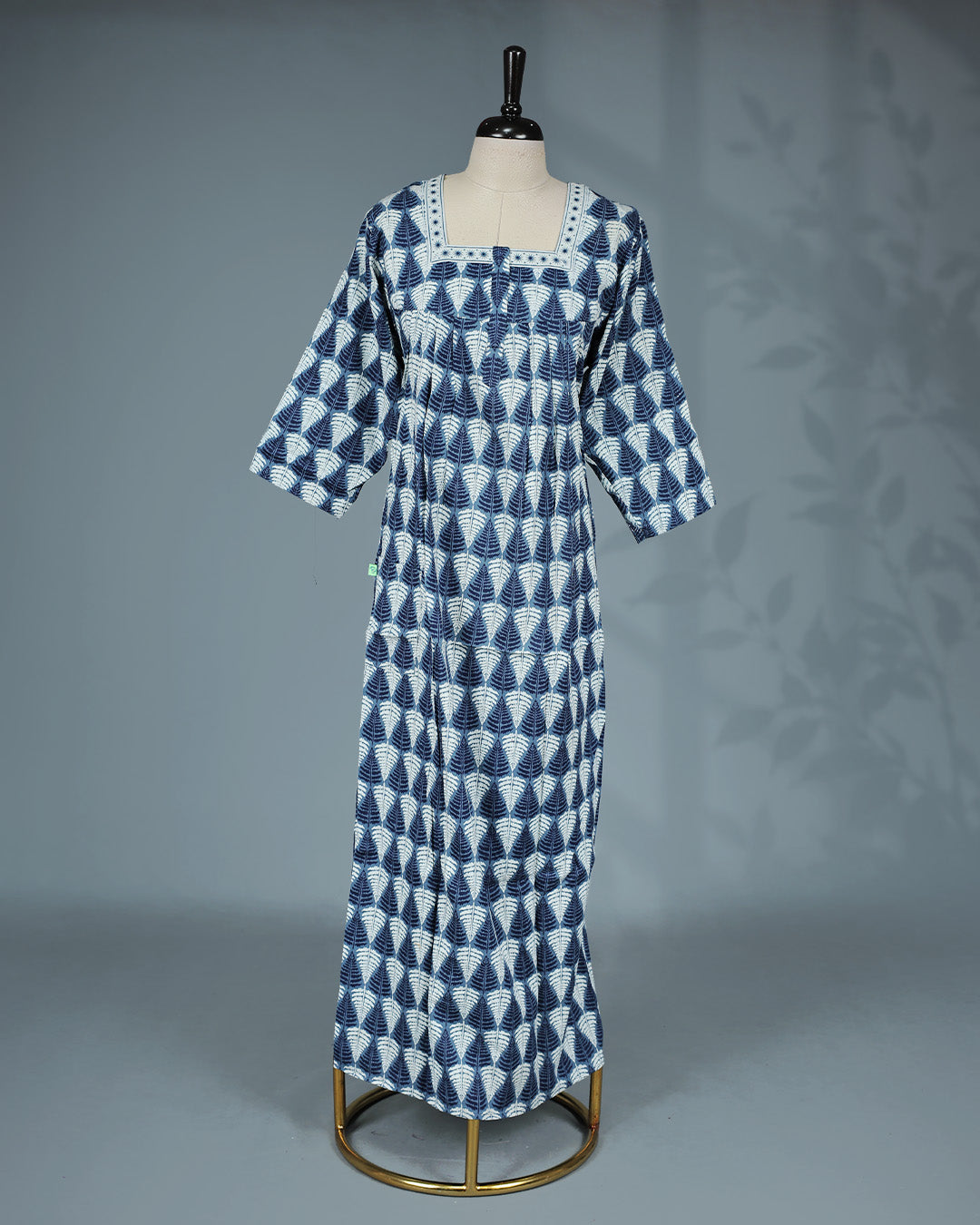 Blue and white leaf printed nighty with a classic square neckline, three-quarter sleeves, contrast border detailing on the yoke, and a relaxed full-length for everyday comfort and timeless elegance.