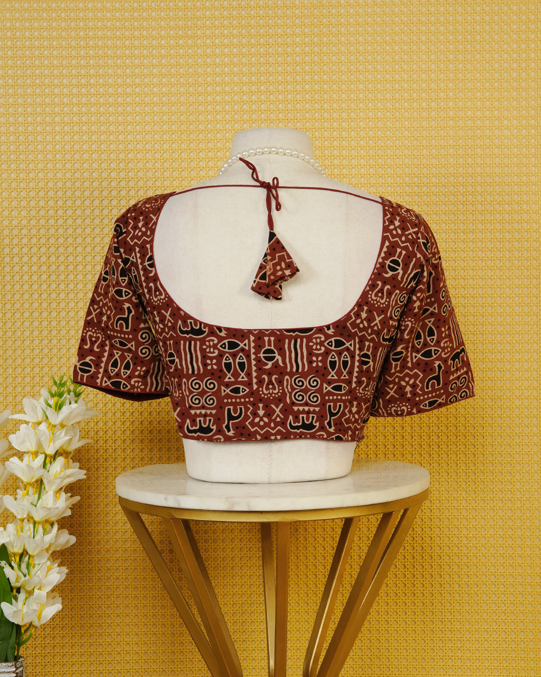 Maroon Colour Printed Blouse Featuring An All Over Tribal Inspired Geometric Motif Pattern, Enhanced With A Round Neckline, Front Button Closure, And Short Sleeves.