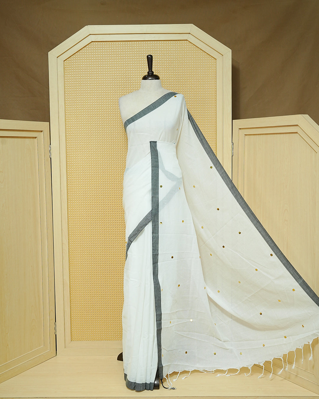 White colour Mul cotton saree featuring Gold Sequins, complemented by Contrast Black simple Border & tassels.