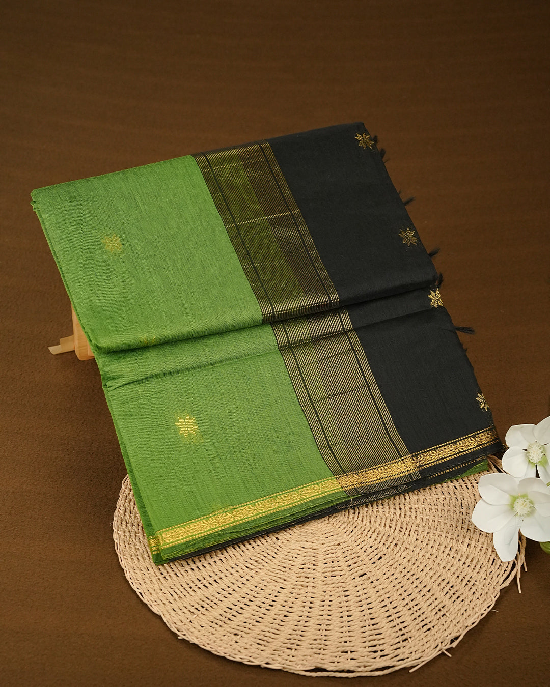 Green colour kalyani cotton saree featuring gold zari Floral pattern on body, complemented by Black colour with Stripes & Floral Gold zari border, paired with matching blouse piece