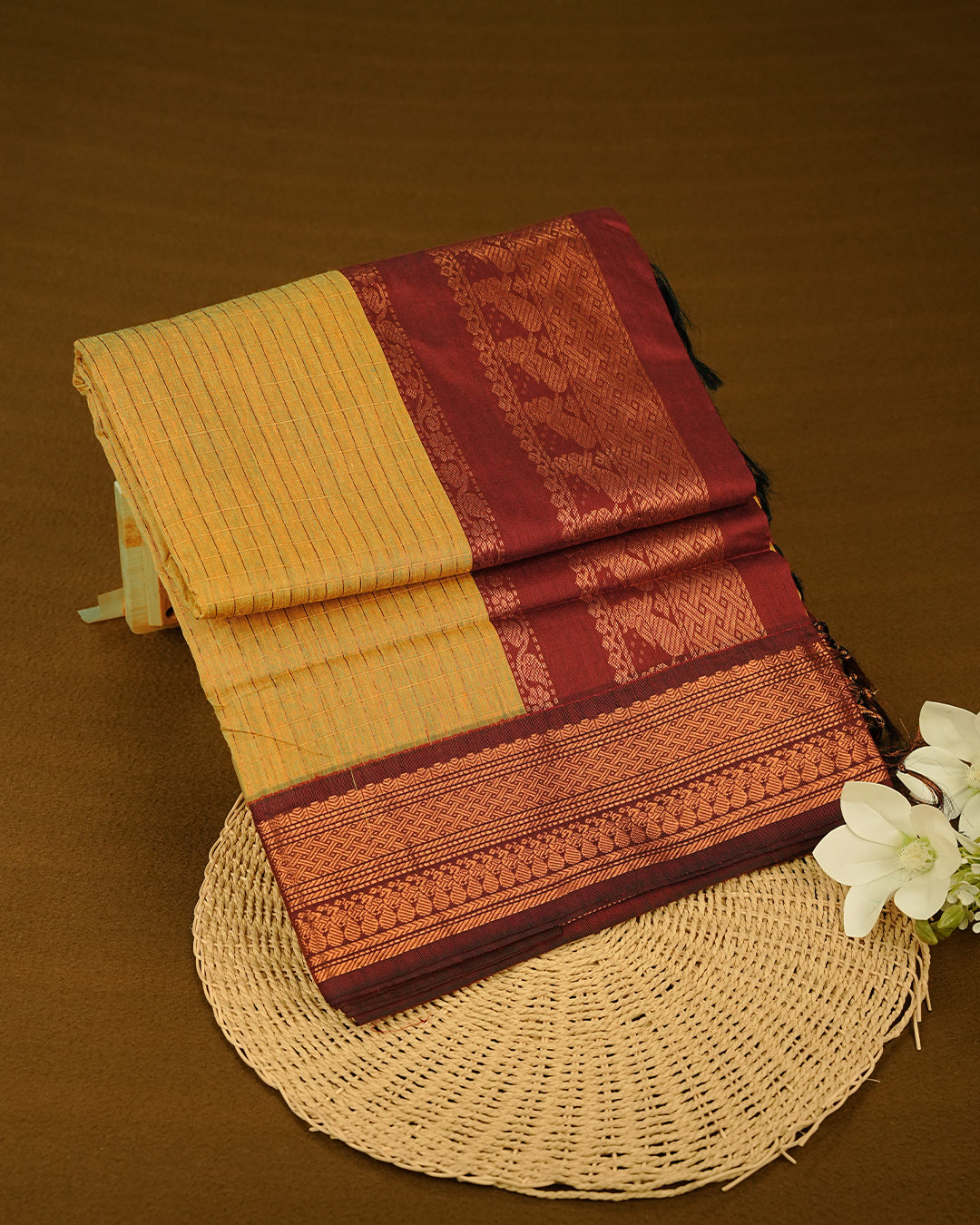 Mustard colour kalyani cotton saree featuring Copper zari check pattern on body, complemented by Brown colour with Antique zari border, paired with matching blouse piece
