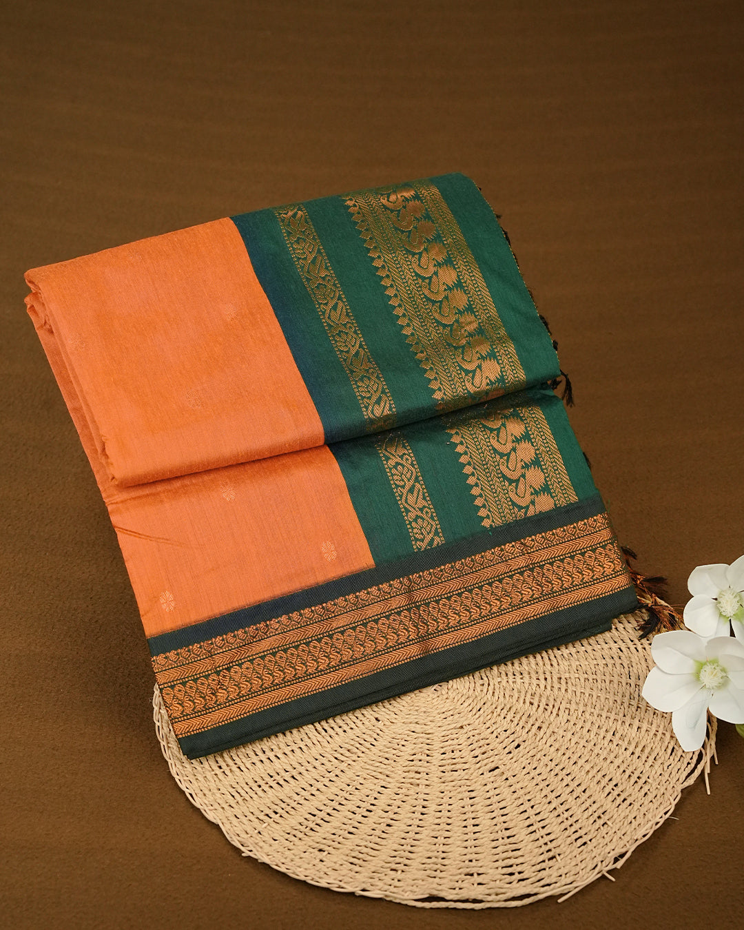 Mustard Orange Colour Kalyani cotton saree featuring antique zari floral buttas on the body, complemented by a Bottle Green contrast pallu with an antique zari peacock border, paired with a matching blouse piece