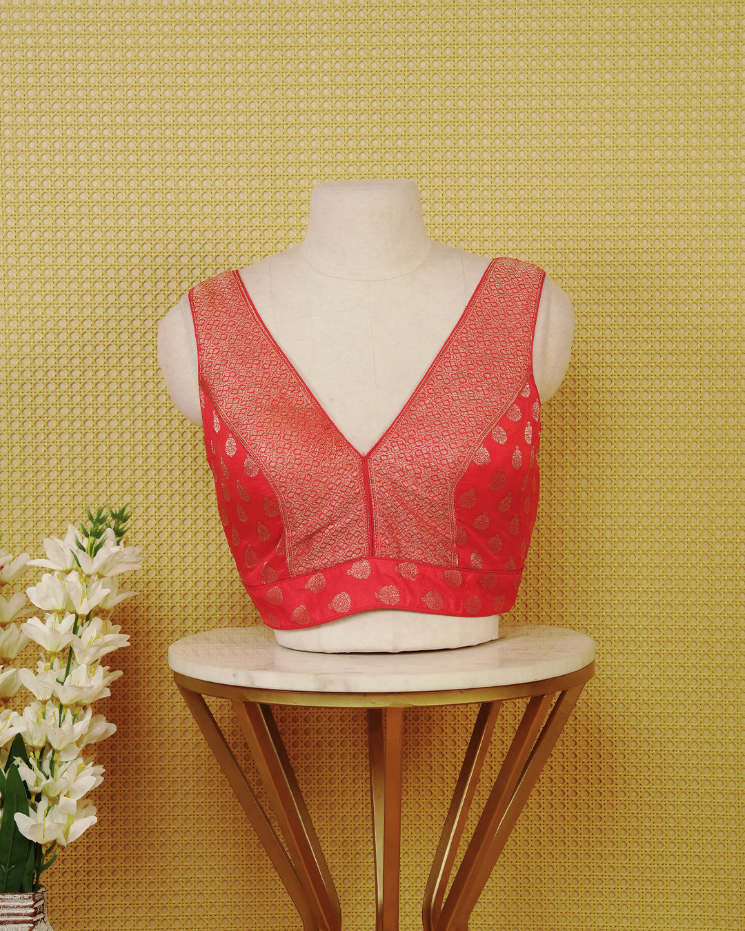 Red colour Sleeveless Blouse Featuring A Stylish V-Neck, Elegant Woven Pattern With Gold Butta Motifs, And A Comfortable Tailored Fit.