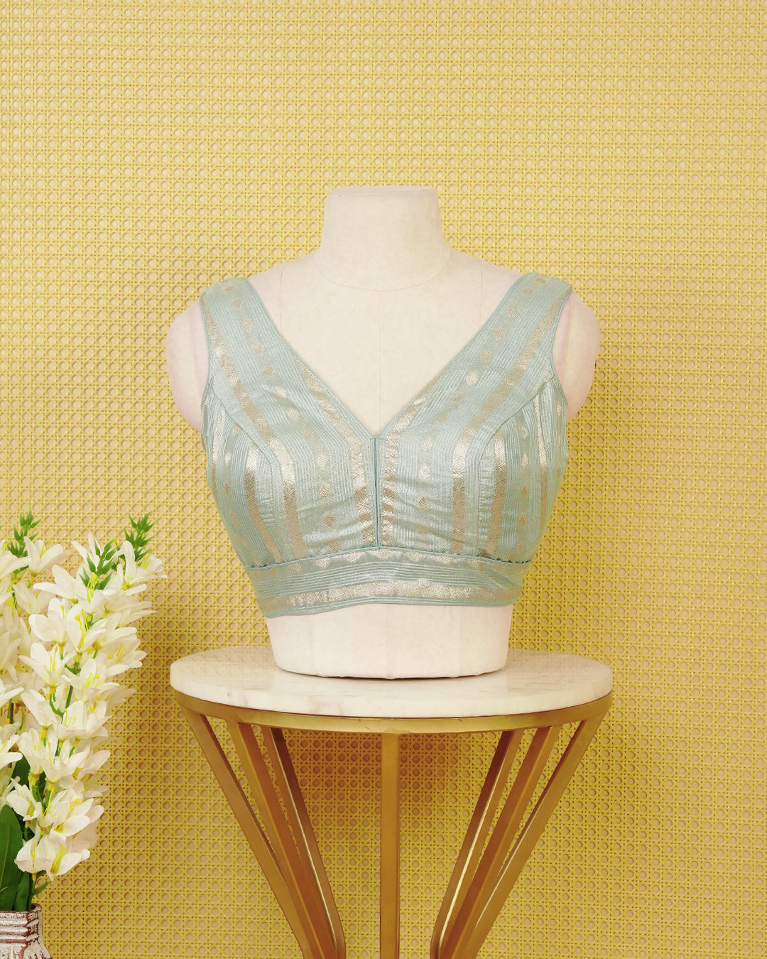 ice Blue colour Sleeveless Blouse Featuring A Stylish V-Neck, Elegant Woven Zari Stripes With Butta Motifs, And A Comfortable Tailored Fit.