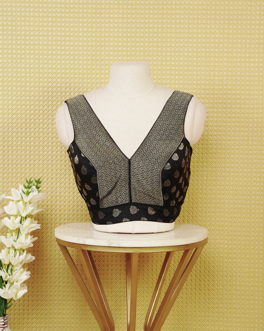 Black colour Sleeveless Blouse Featuring A Stylish V-Neck, Elegant Woven Pattern With Gold Butta Motifs, And A Comfortable Tailored Fit.