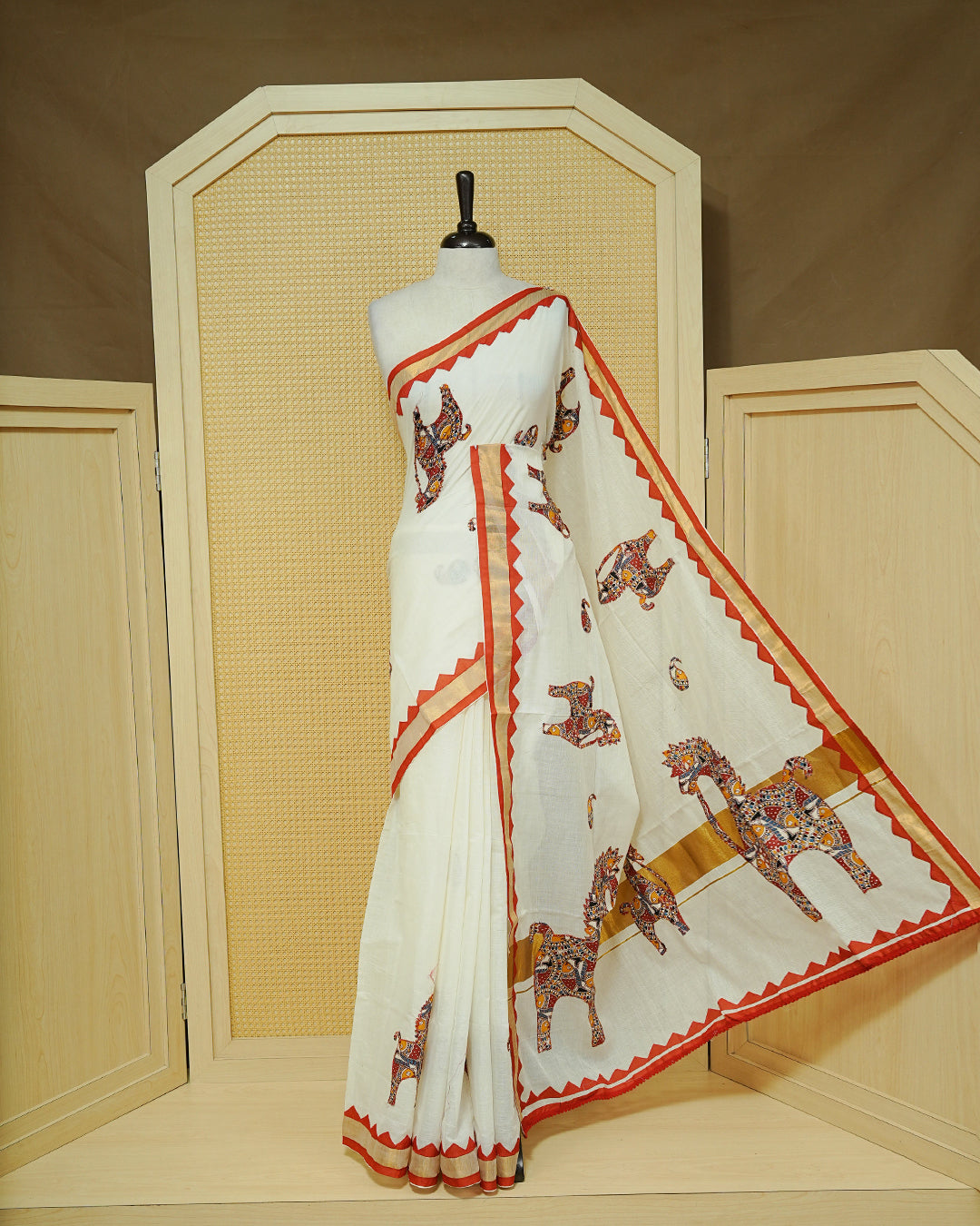 Cream colour Kerala saree Featuring Ajrakh Inspired Buttas Red Horse pattern, Gold zari border, comes with matching blouse piece.