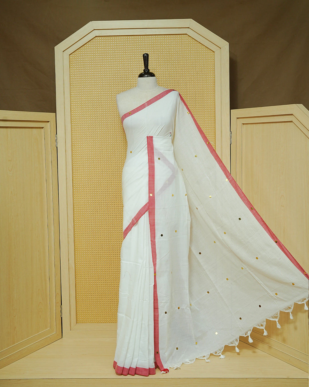 White colour Mul cotton saree featuring Gold Sequins, complemented by Contrast Red simple Border & tassels.