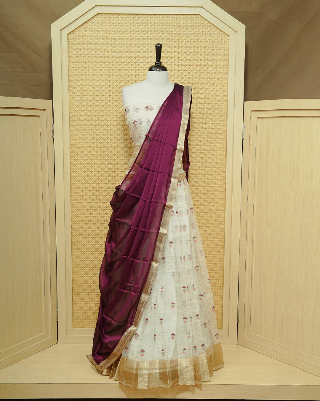 Cream colour Semi stitched Dhavani set featuring Gold zari checked pattern with floral motifs on skirt with traditional border, comes with contrast Colour Dupatta & matching blouse piece.