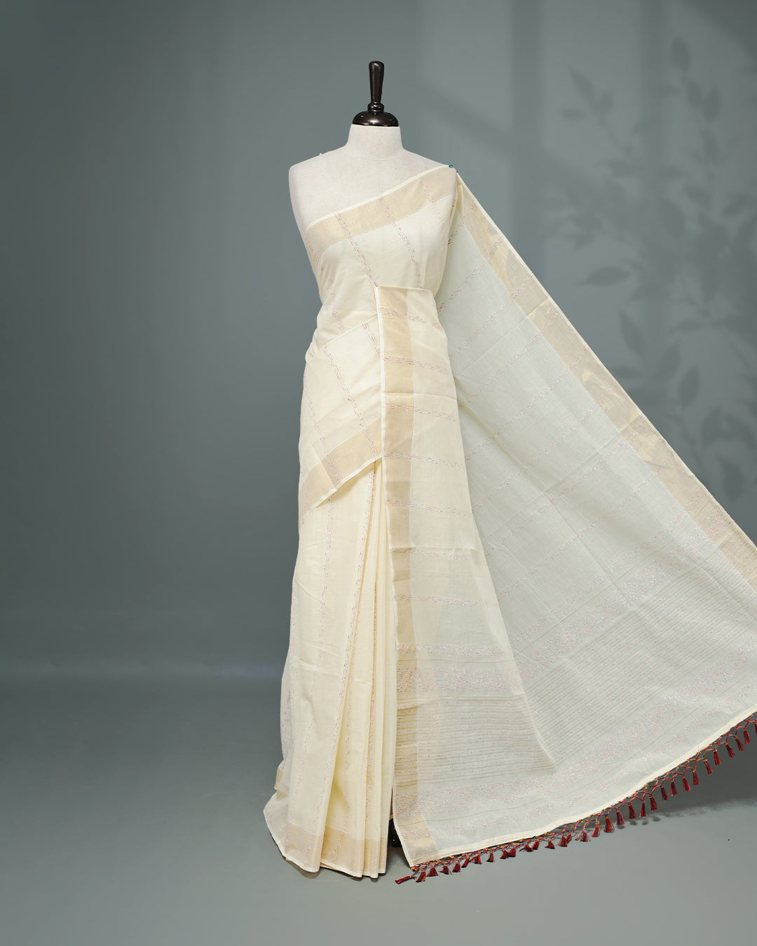 Cream colour Cotton kerala saree featuring Multicolour & gold Strips on body, complemented by Gold zari Border, paired with matching blouse piece.