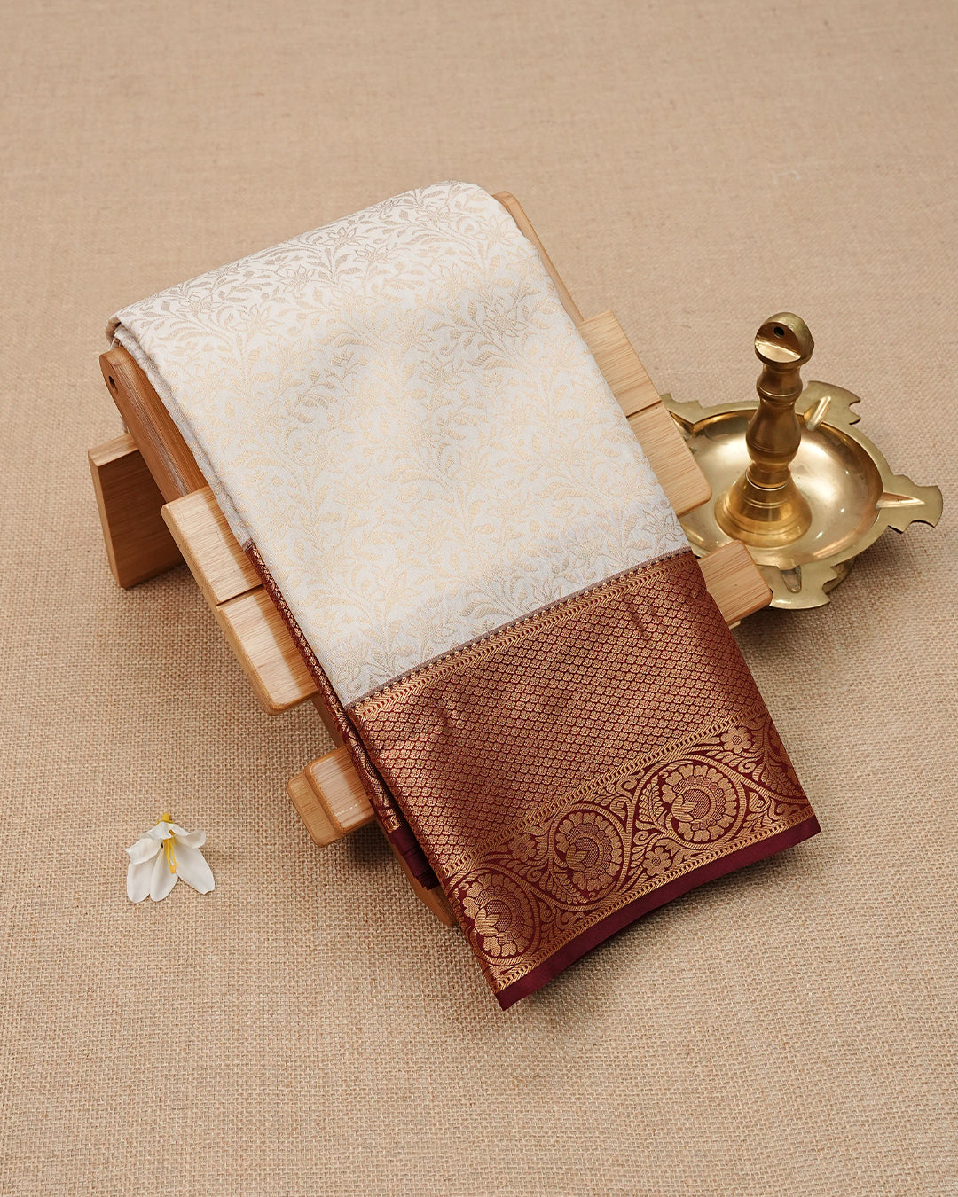 Cream colour semi wedding saree featuring gold zari Floral kodi Pattern on body, contrast Maroon colour with traditional border, paired with matching blouse piece.