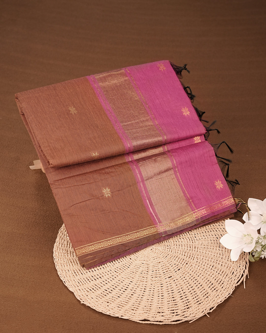 Brown colour Kalyani cotton saree featuring a gold zari floral pattern on the body, complemented by a magenta pallu with gold zari stripes and a floral zari border, paired with a matching blouse piece