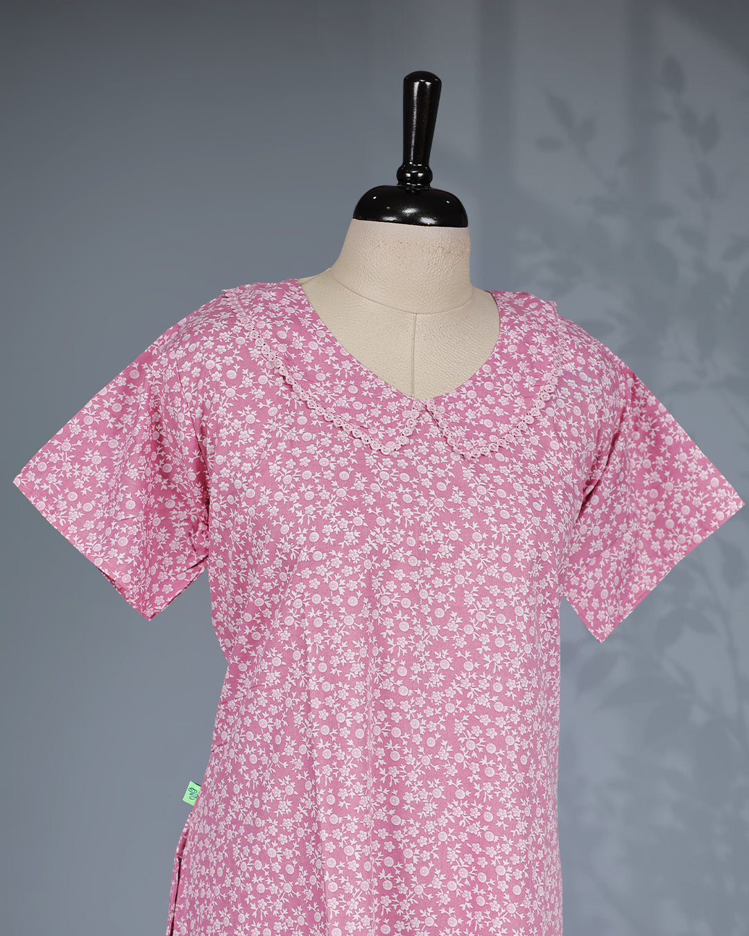 Blush pink colour nighty featuring white floral prints ob body, a U Shaped neckline with lace-trimmed Peter Pan collar, short sleeves, and a ruffled Mid-length fit