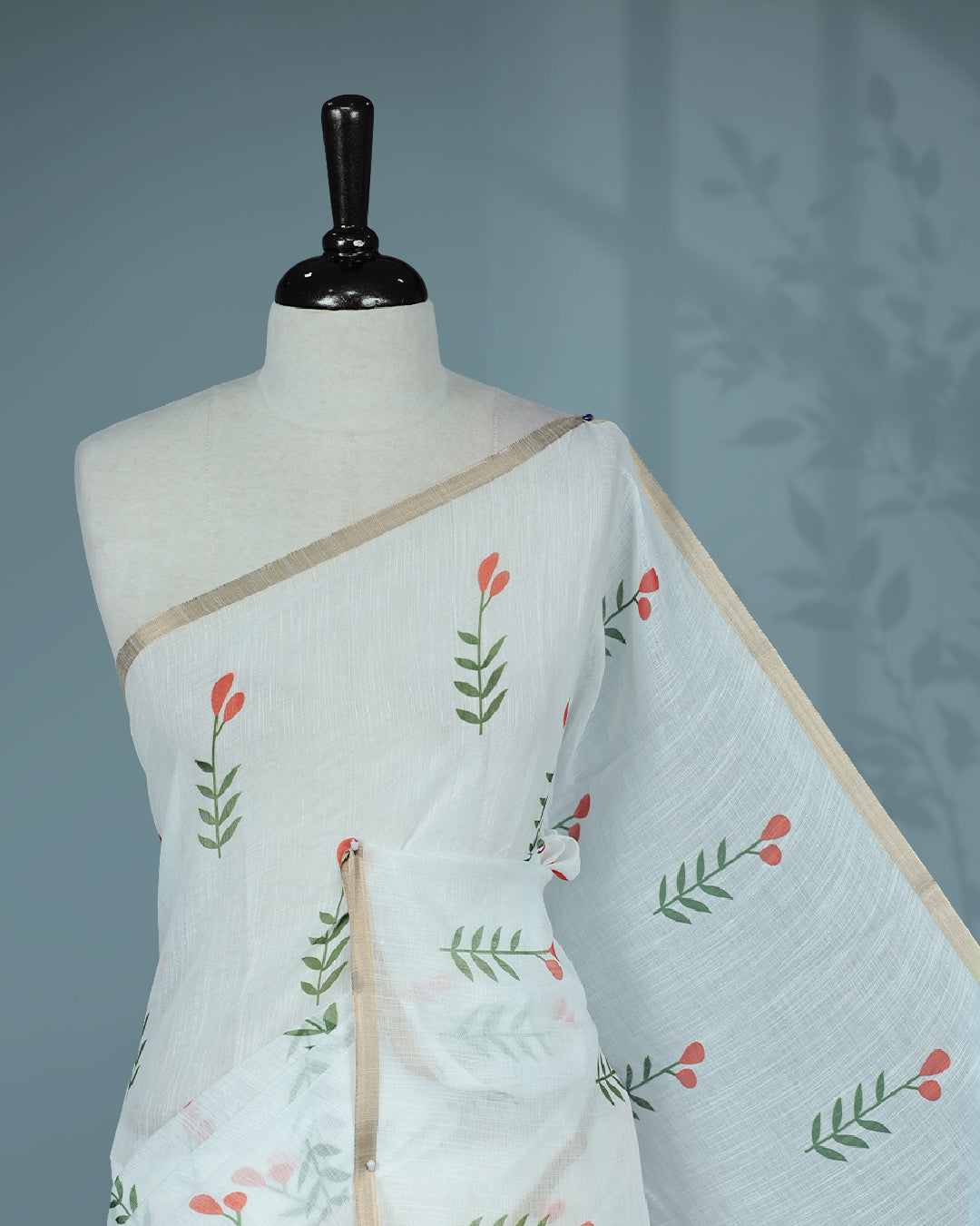 Off-white linen saree featuring beautiful orange floral and leafy prints on the body, complemented by a tissue piping border and a contrasting pallu. Paired with a matching blouse piece.