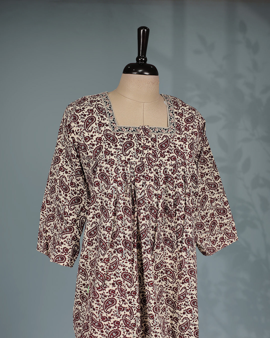 Cream and maroon paisley printed nighty with a classic square neckline, three-quarter sleeves, elegant border detailing and a relaxed full-length silhouette for everyday comfort and timeless style.