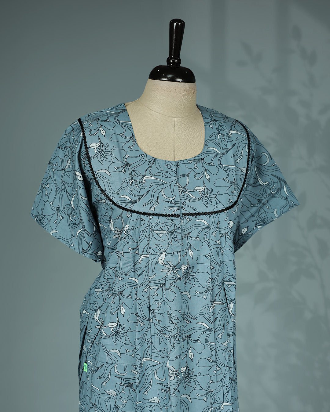 Dusty blue colour floral print nighty featuring an elegant U-shaped neckline with delicate black lace trim, soft pleated detailing, short sleeves and a relaxed full-length for all-day comfort and effortless style.