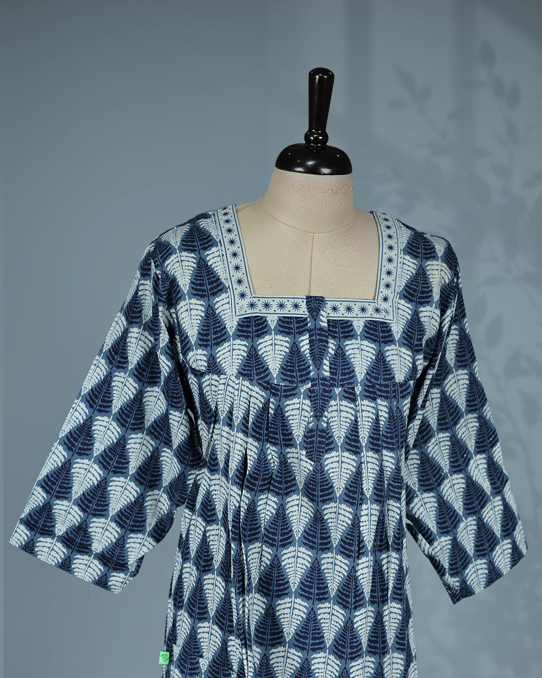 Blue and white leaf printed nighty with a classic square neckline, three-quarter sleeves, contrast border detailing on the yoke, and a relaxed full-length for everyday comfort and timeless elegance.