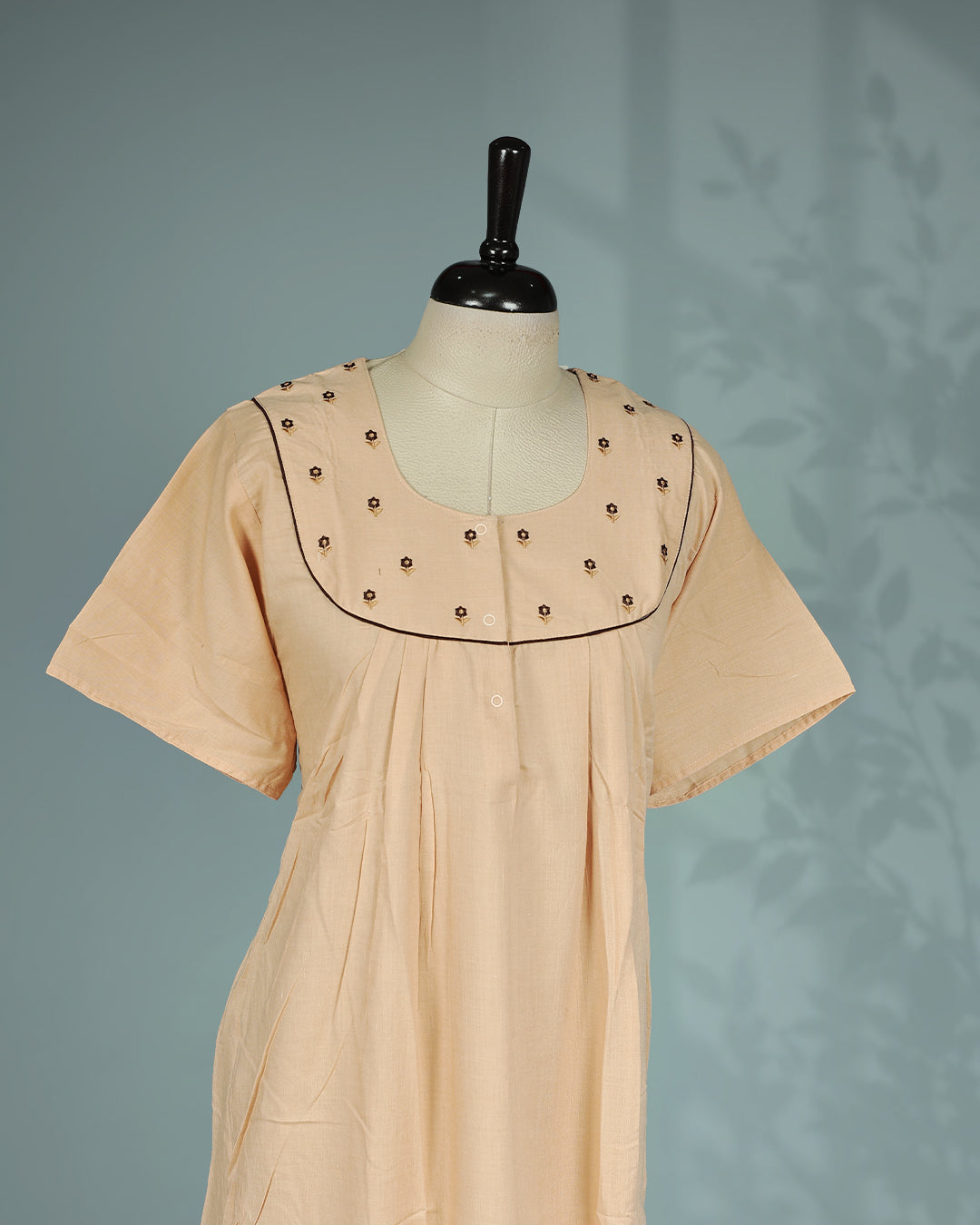 Peach solid nighty with a classic square neckline, short sleeves, delicate floral embroidery on the yoke, subtle contrast piping, and a relaxed full-length for everyday comfort and elegant simplicity.