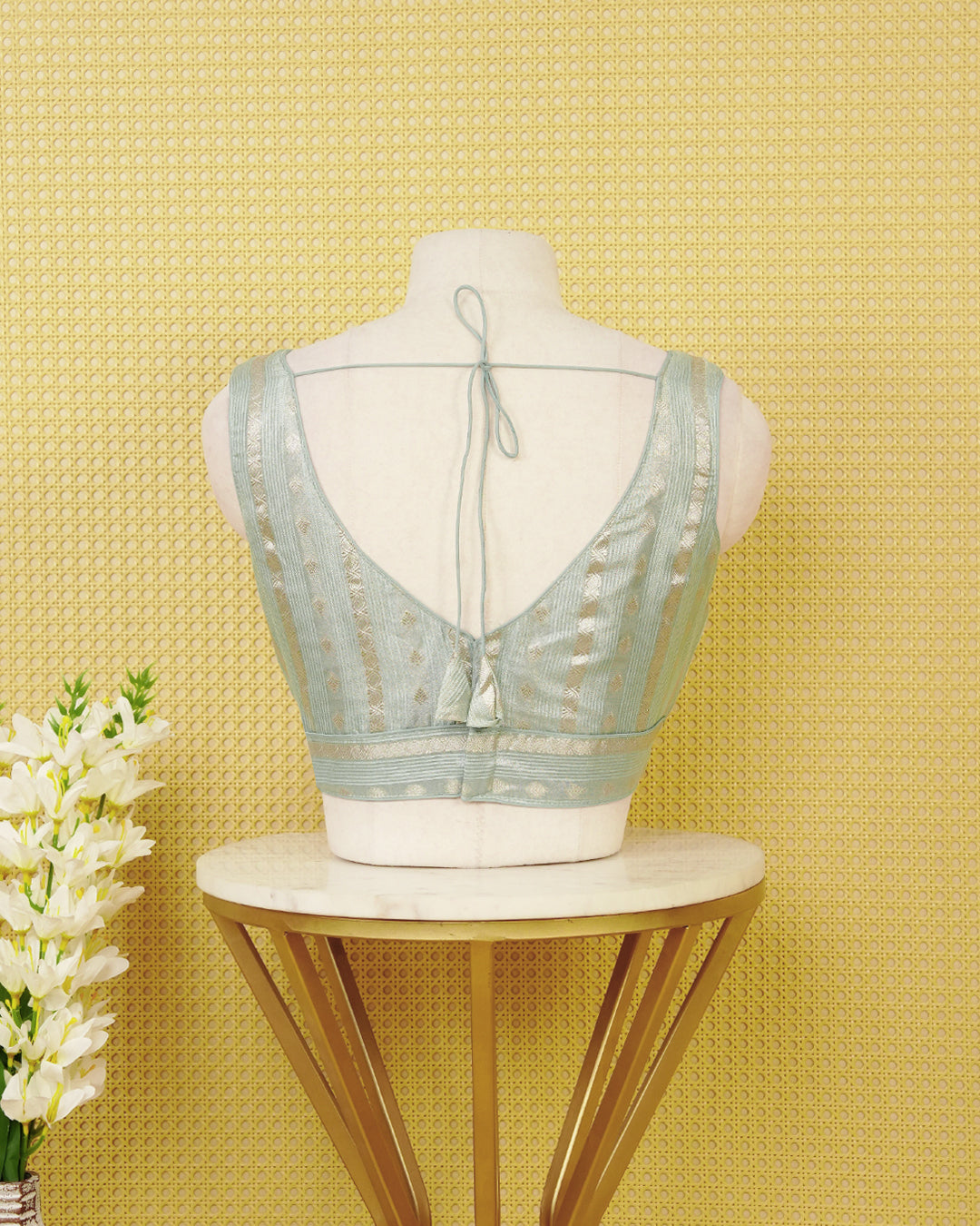 ice Blue colour Sleeveless Blouse Featuring A Stylish V-Neck, Elegant Woven Zari Stripes With Butta Motifs, And A Comfortable Tailored Fit.