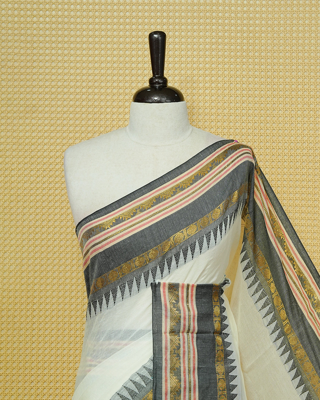 Cream Mul Cotton Saree featuring an elegant plain body, complemented by a grey contrast border with gold zari and subtle Red stripe detailing, finished with black tassels.