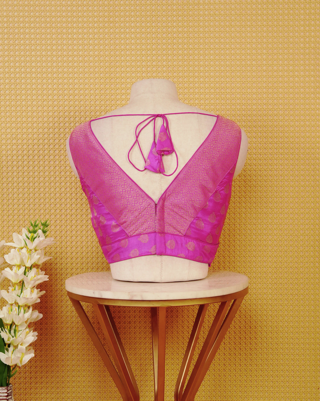 Magenta colour Sleeveless Blouse Featuring A Stylish V-Neck, Elegant Woven Pattern With Gold Butta Motifs, And A Comfortable Tailored Fit.
