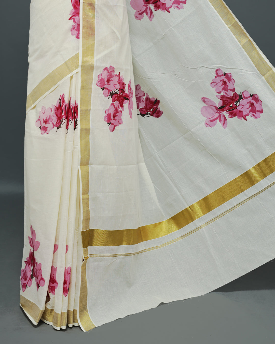 Cream colour Cotton kerala saree featuring Magenta colour floral Print on the body, complemented by a gold zari Border, paired with a matching blouse piece.