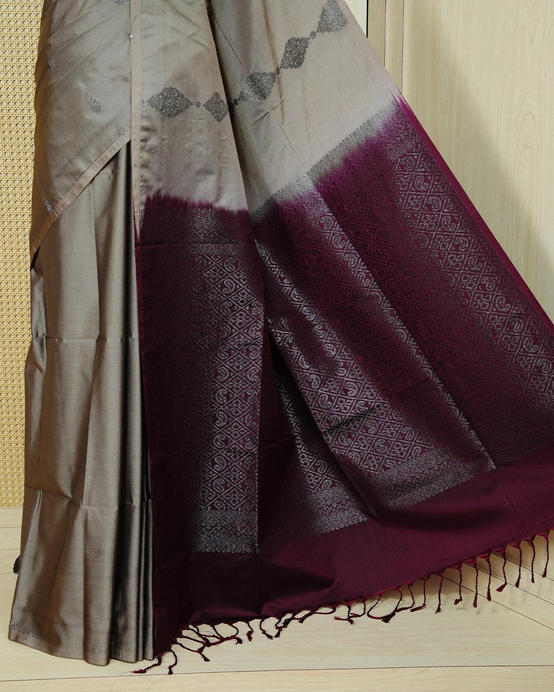 Taupe beige colour soft silk saree featuring antique zari motifs on body with contrast dark maroon colour pallu & paired with matching blouse piece.