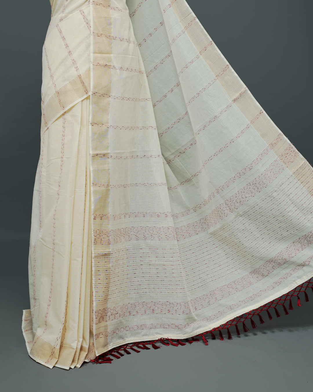 Cream colour Cotton kerala saree featuring Maroon & gold Strips on body, complemented by Gold zari Border, paired with matching blouse piece.