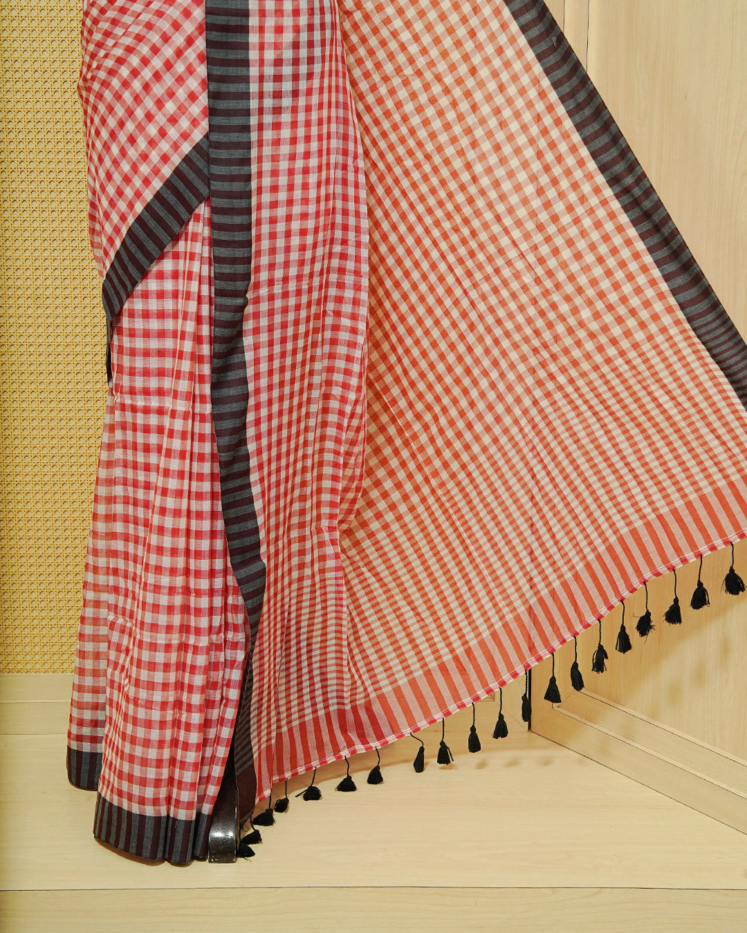 Red & Off-White Checked Mul Cotton Saree featuring an elegant all-over checked pattern, complemented by a black striped contrast border and matching black tassels.
