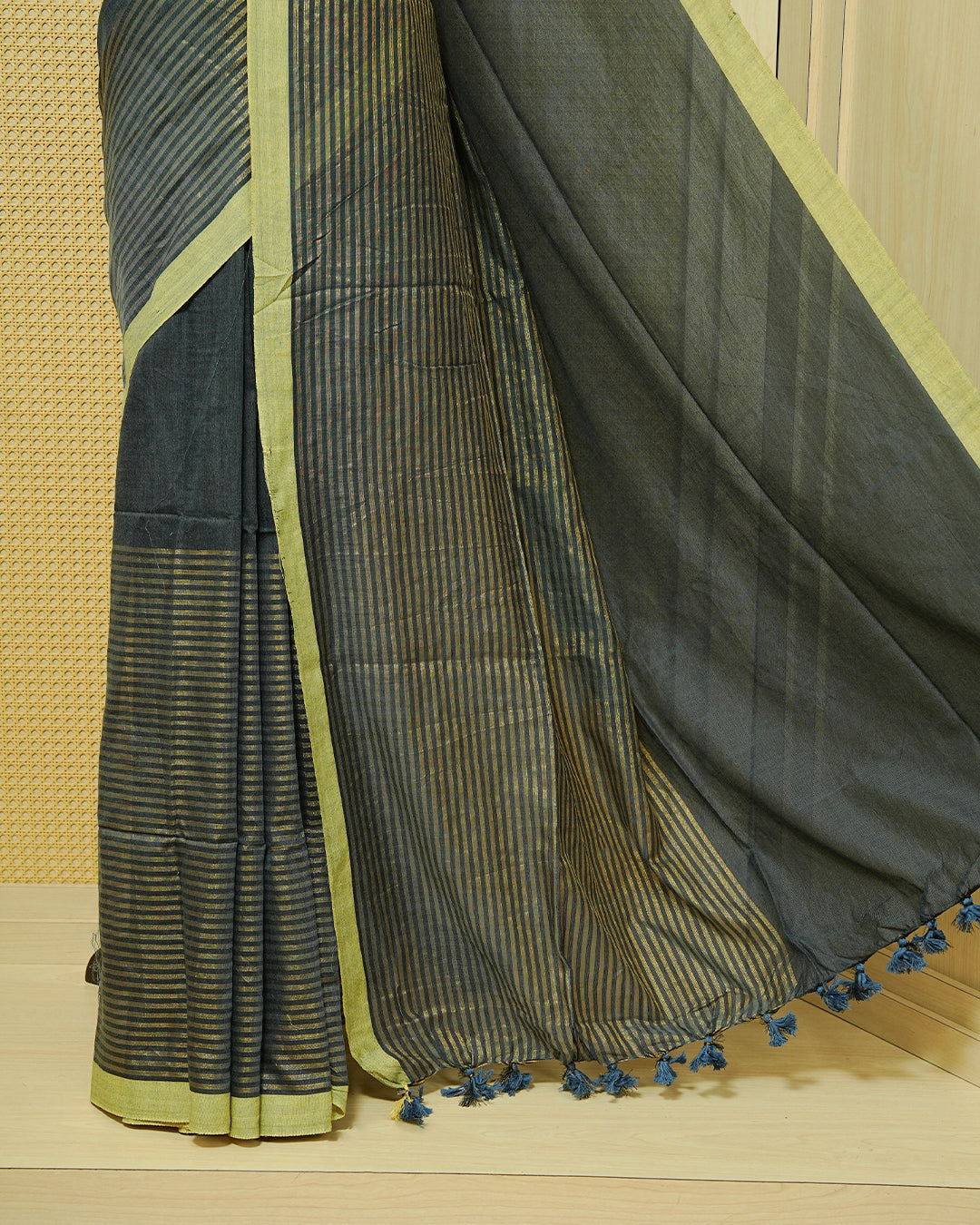 Grey Colour Half & Half Mul cotton saree featuring Gold zari Stripes on one side, Complemented by contrast Green colour Border & tassels.